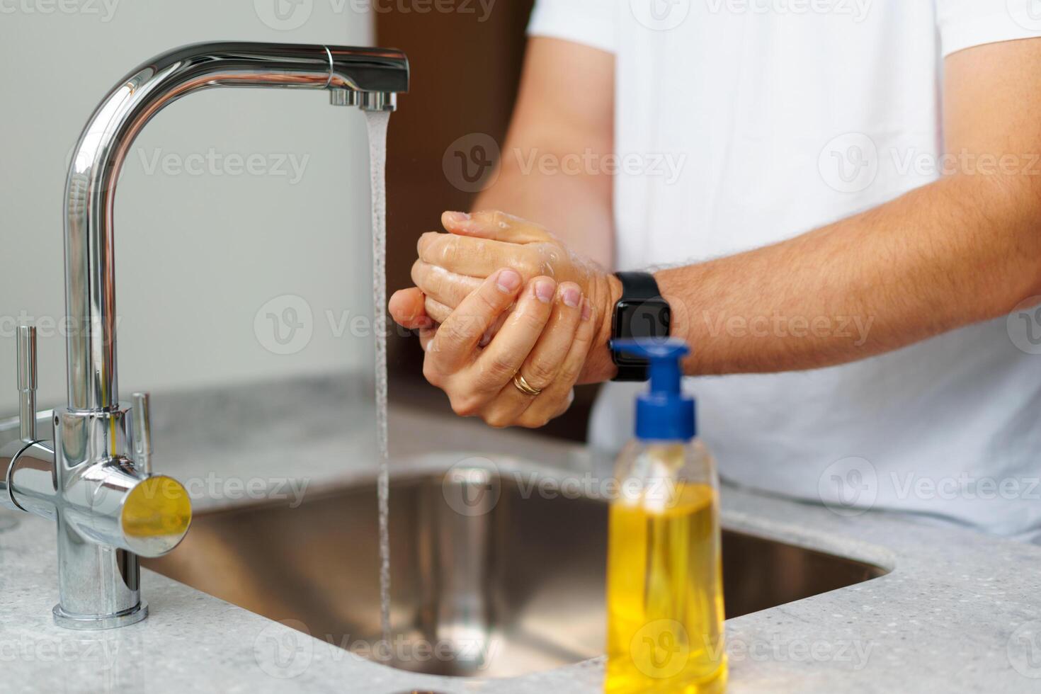 Man washing hands with soap in a sink at his home photo