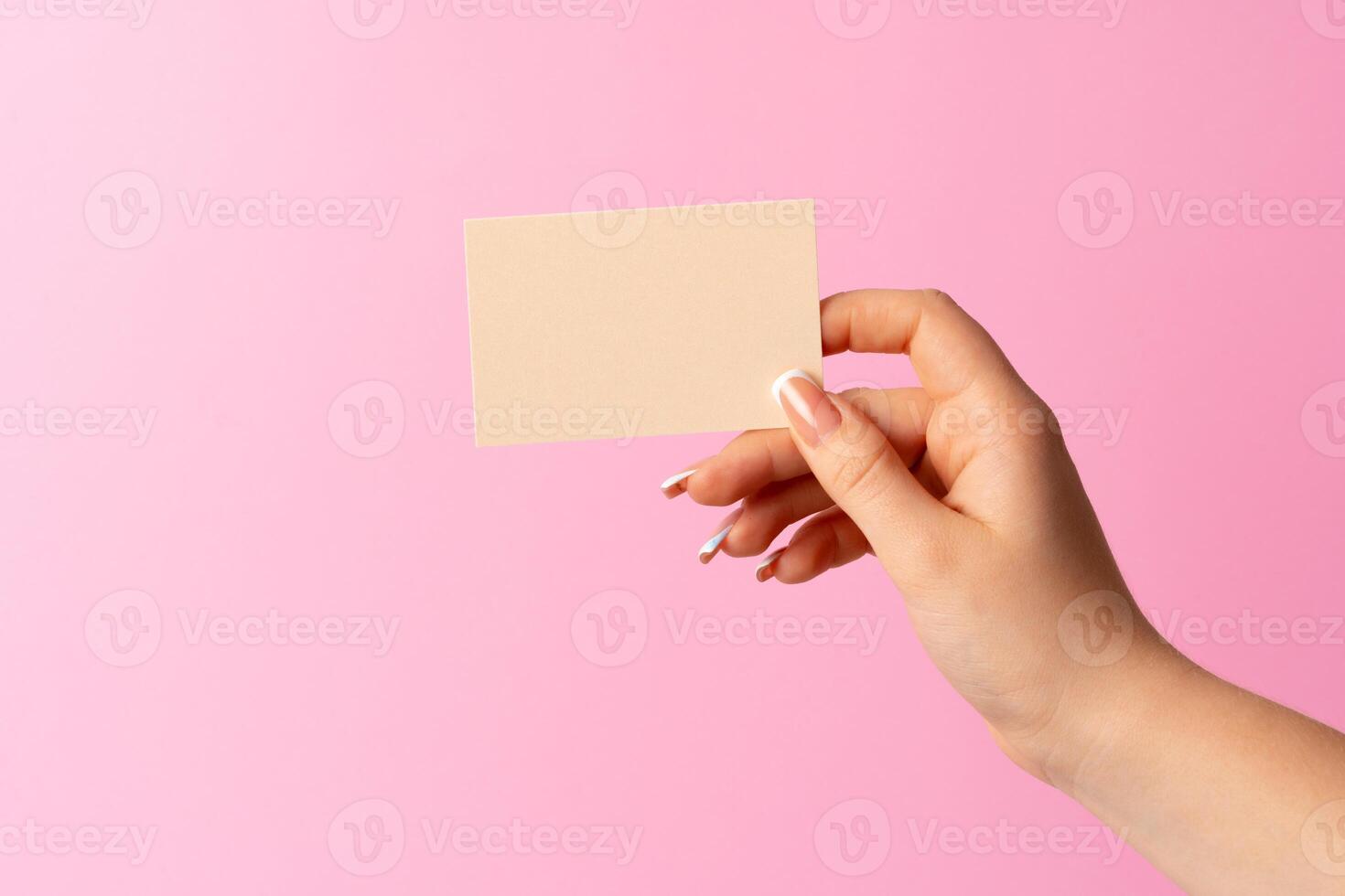 Woman hand showing blank business card on pink background. photo