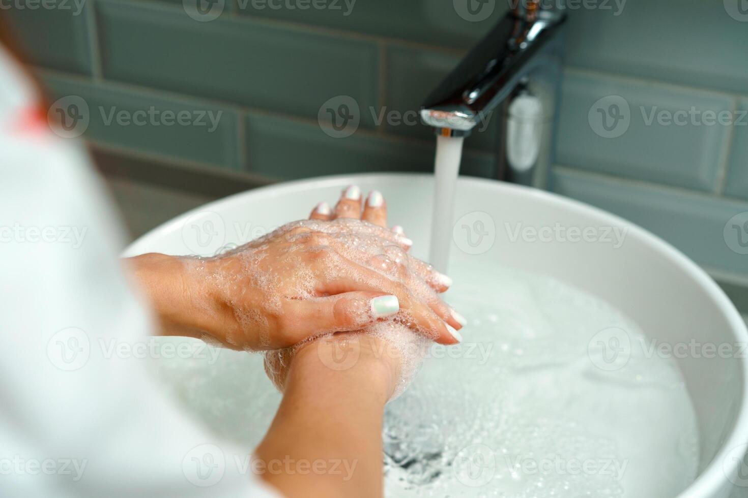 Close up of a woman washing her hands in a bathroom sink photo