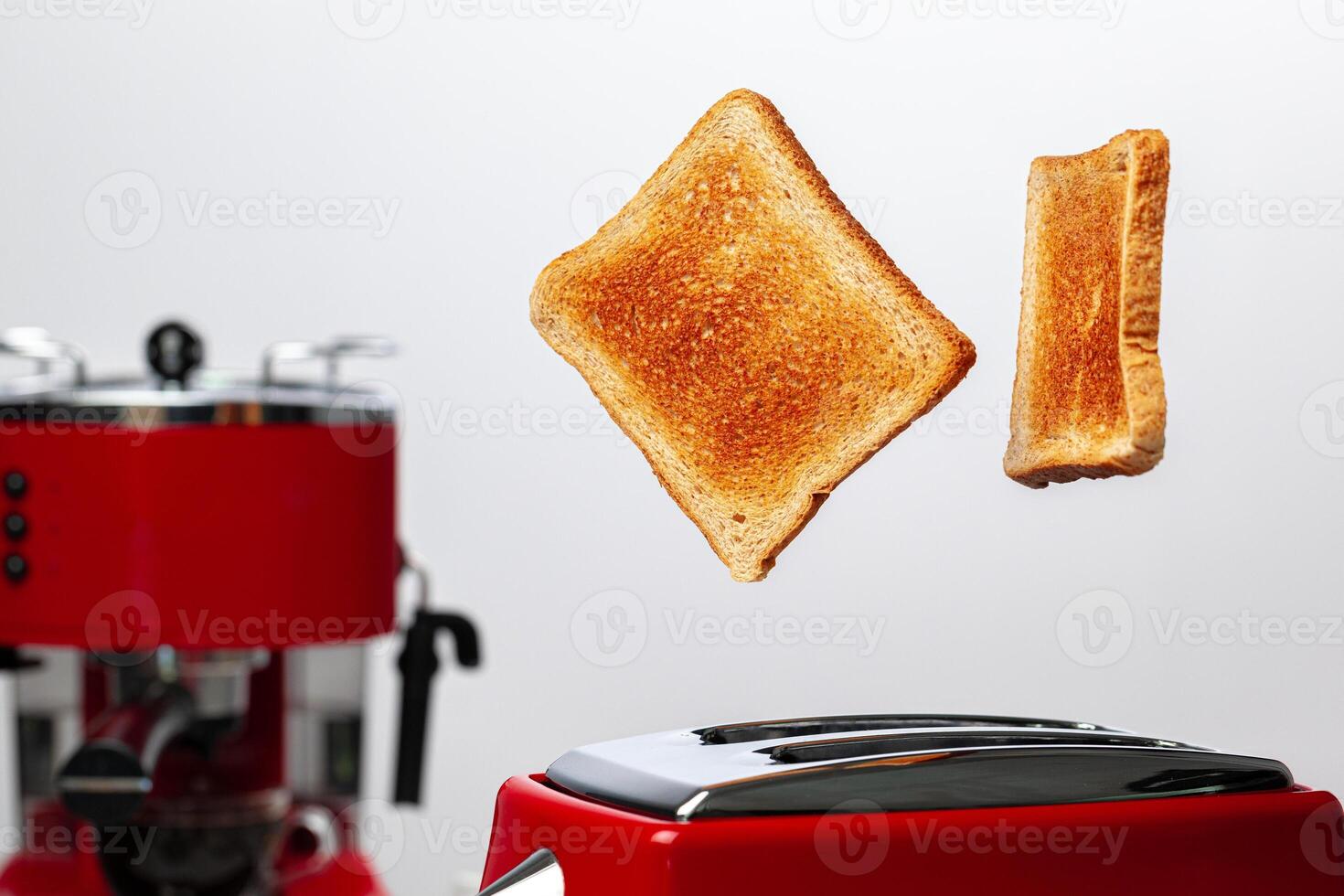 Two toasts jumping out of red toaster against white background photo