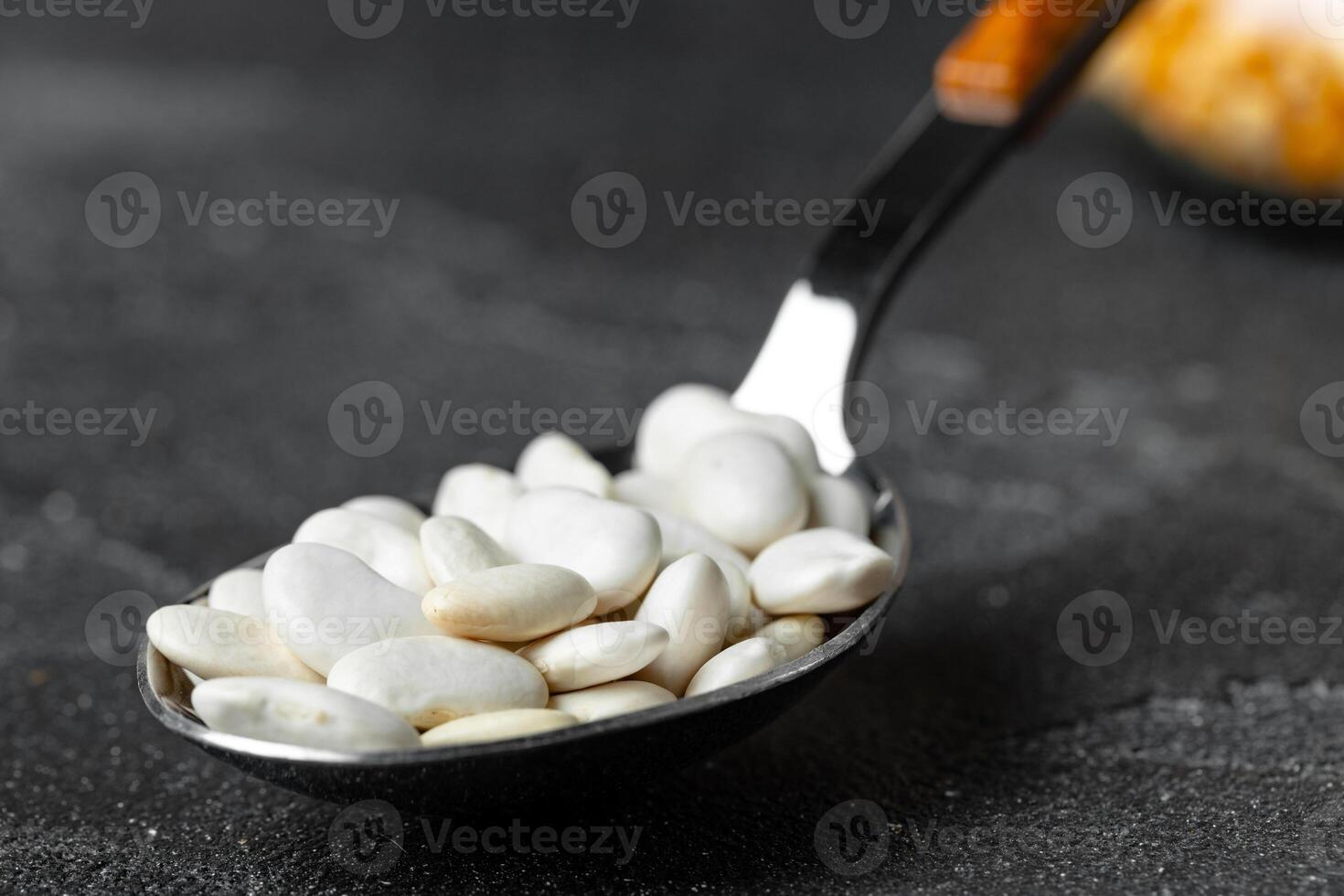 Heap of uncooked beans in a spoon on kitchen table photo