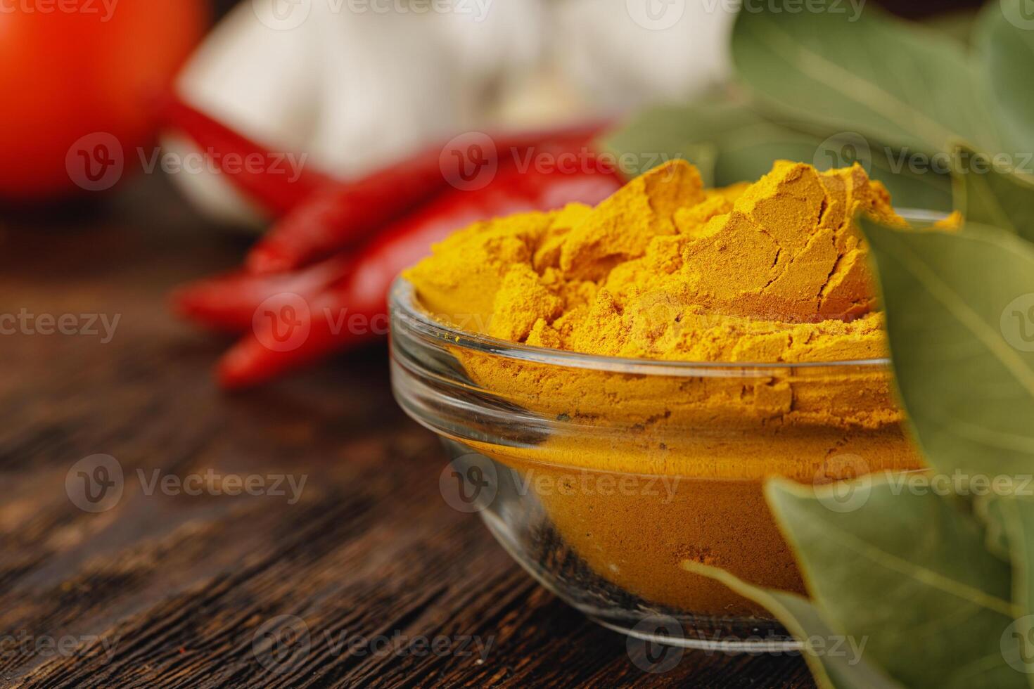 Turmeric powder in glass bowl on wooden table close up photo