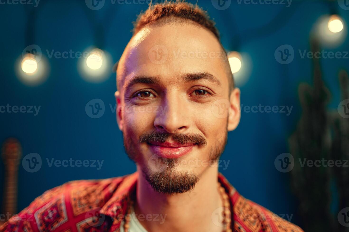 Portrait of a positive handsome caucasian guy with dreadlocks against blue background photo