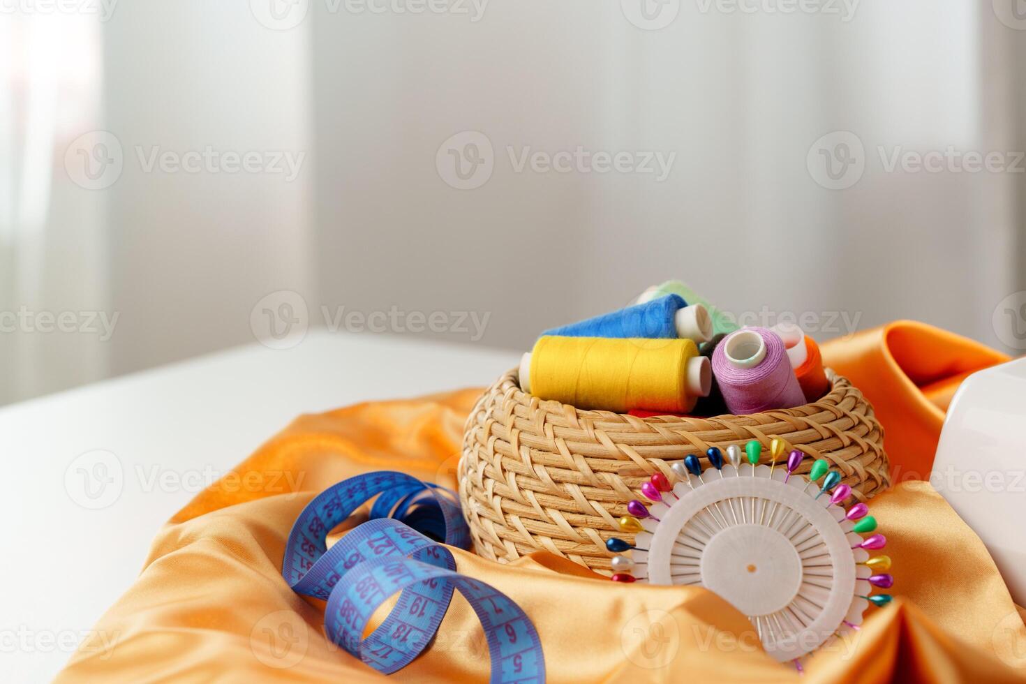 A woven basket filled with colorful sewing threads on a wooden table photo
