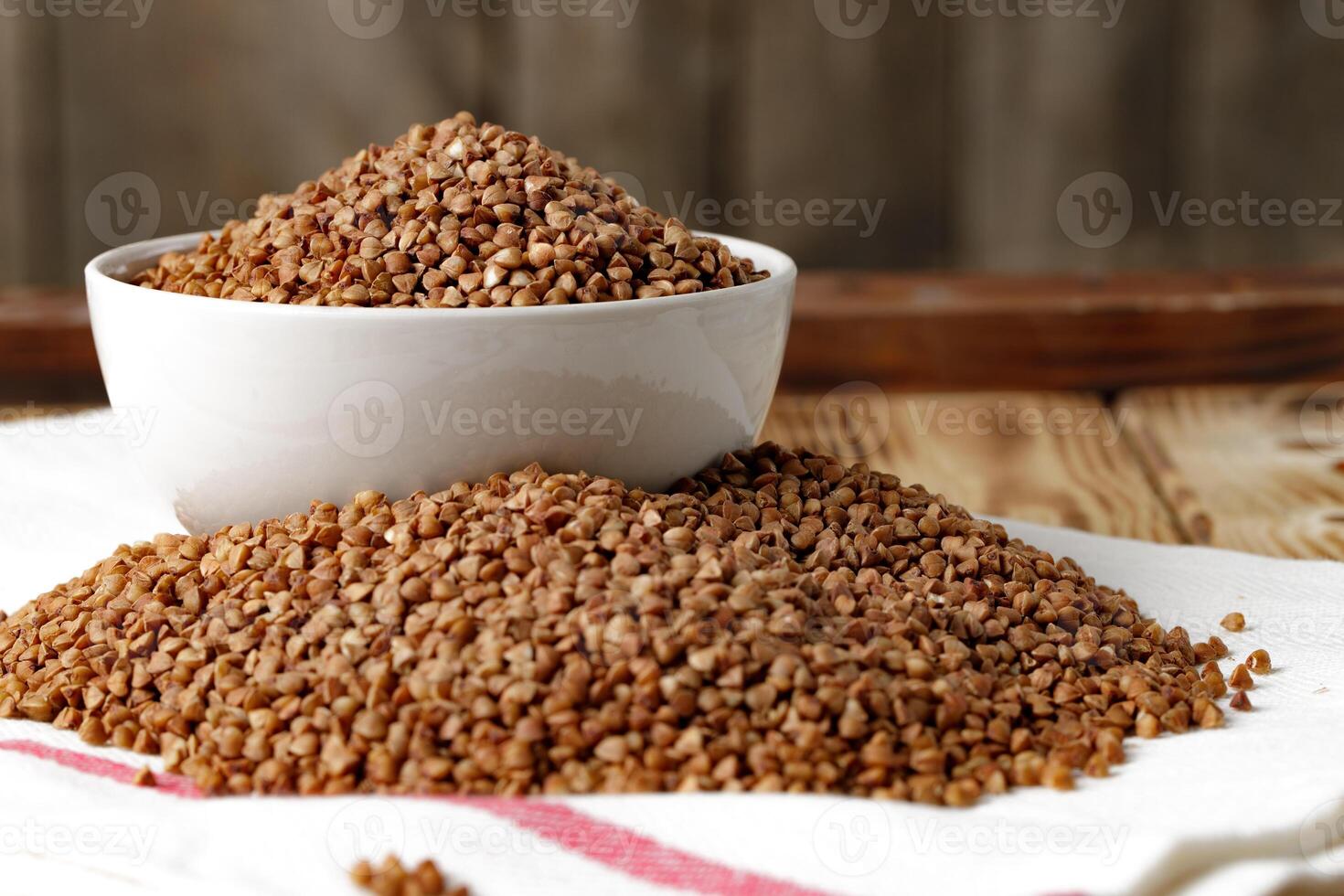 Bowl of raw uncooked buckwheat on wooden table photo