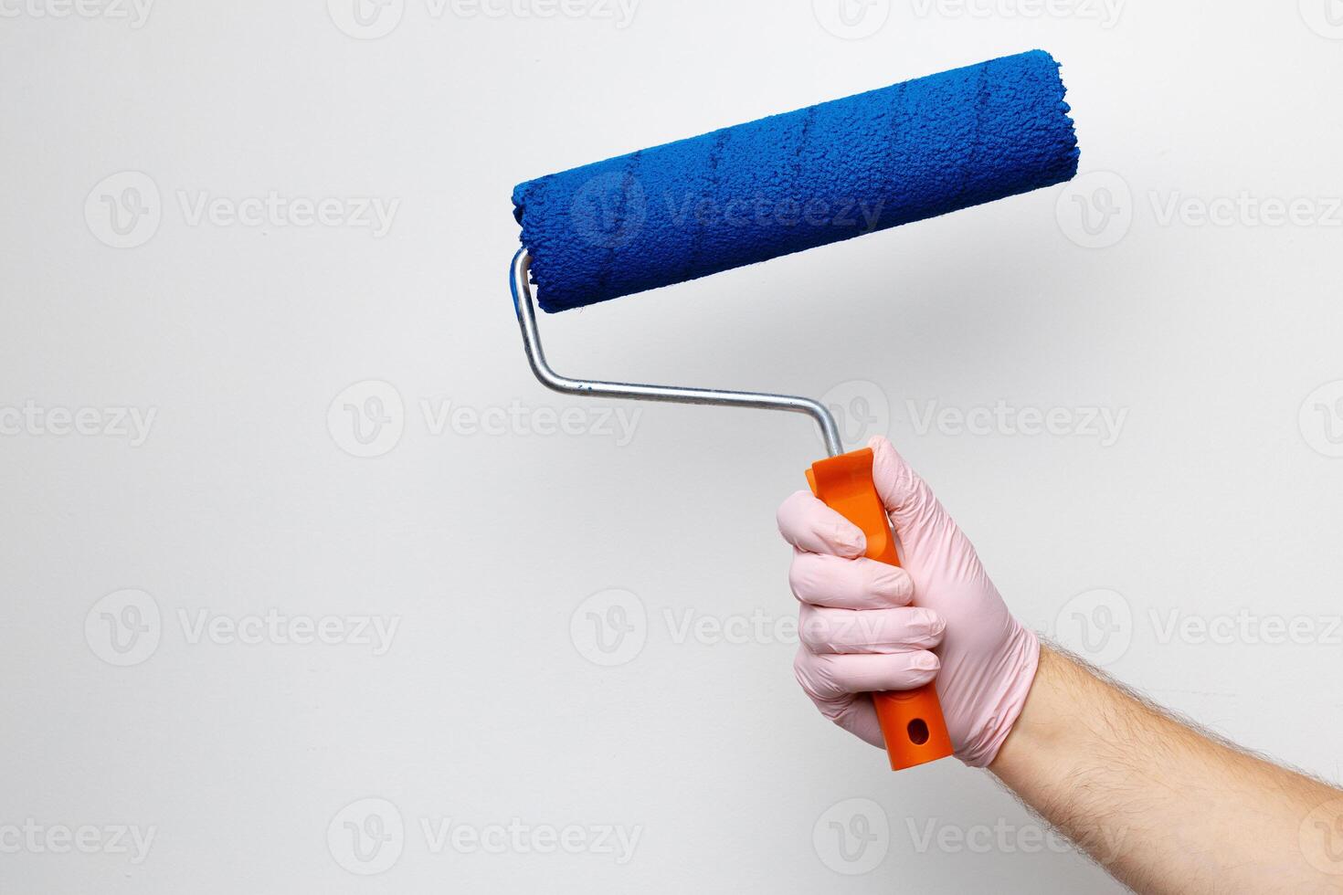 Gloved male hand painting wall into classic blue color photo
