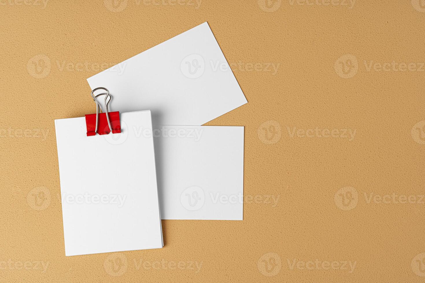 Pile of white businesscards with a clip on beige background photo
