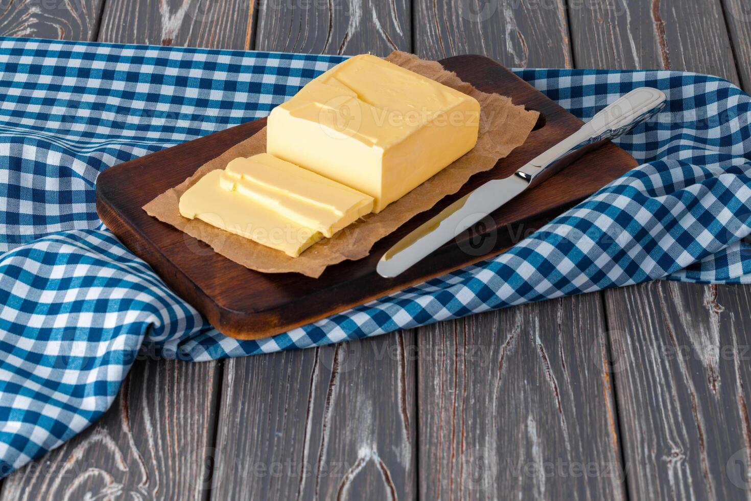 Wooden board with butter on blue checkered napkin photo