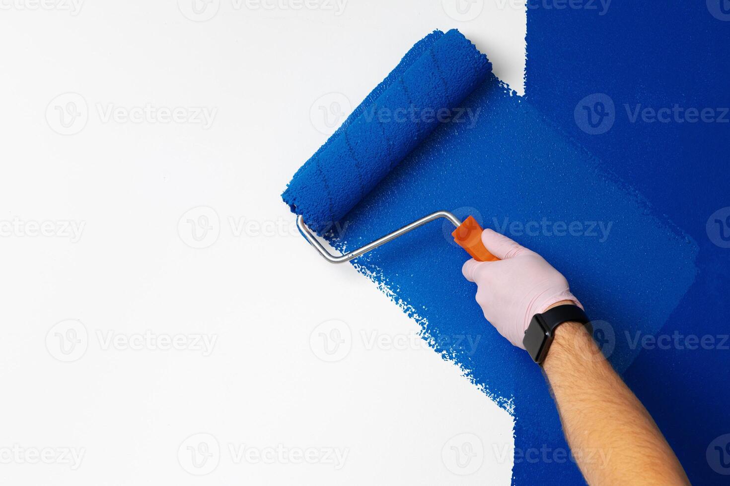 Gloved male hand painting wall into classic blue color photo