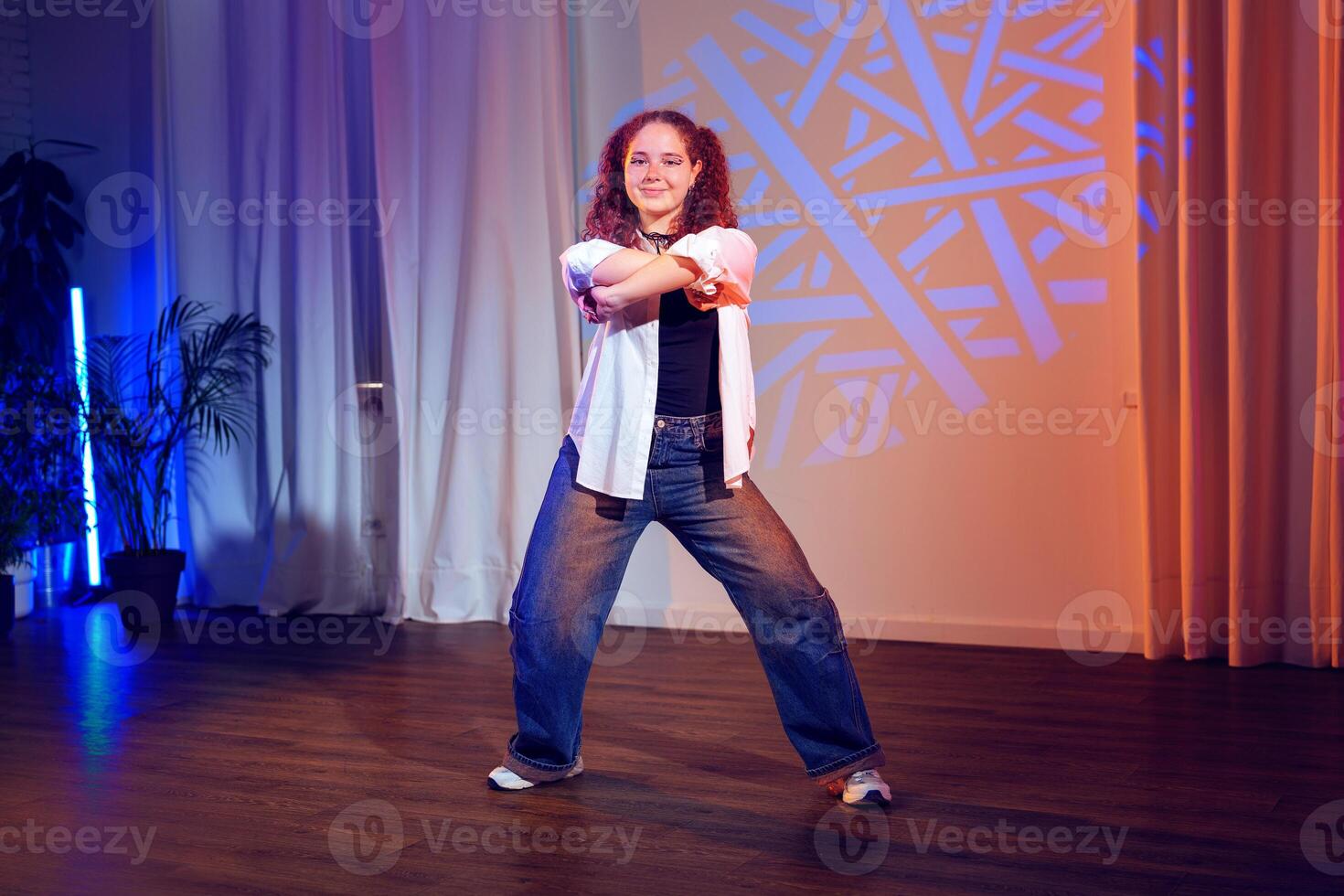 A young woman dances in a studio with blue lighting photo