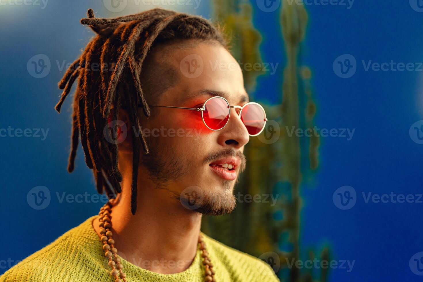 Portrait of a positive handsome caucasian guy with dreadlocks against blue background photo