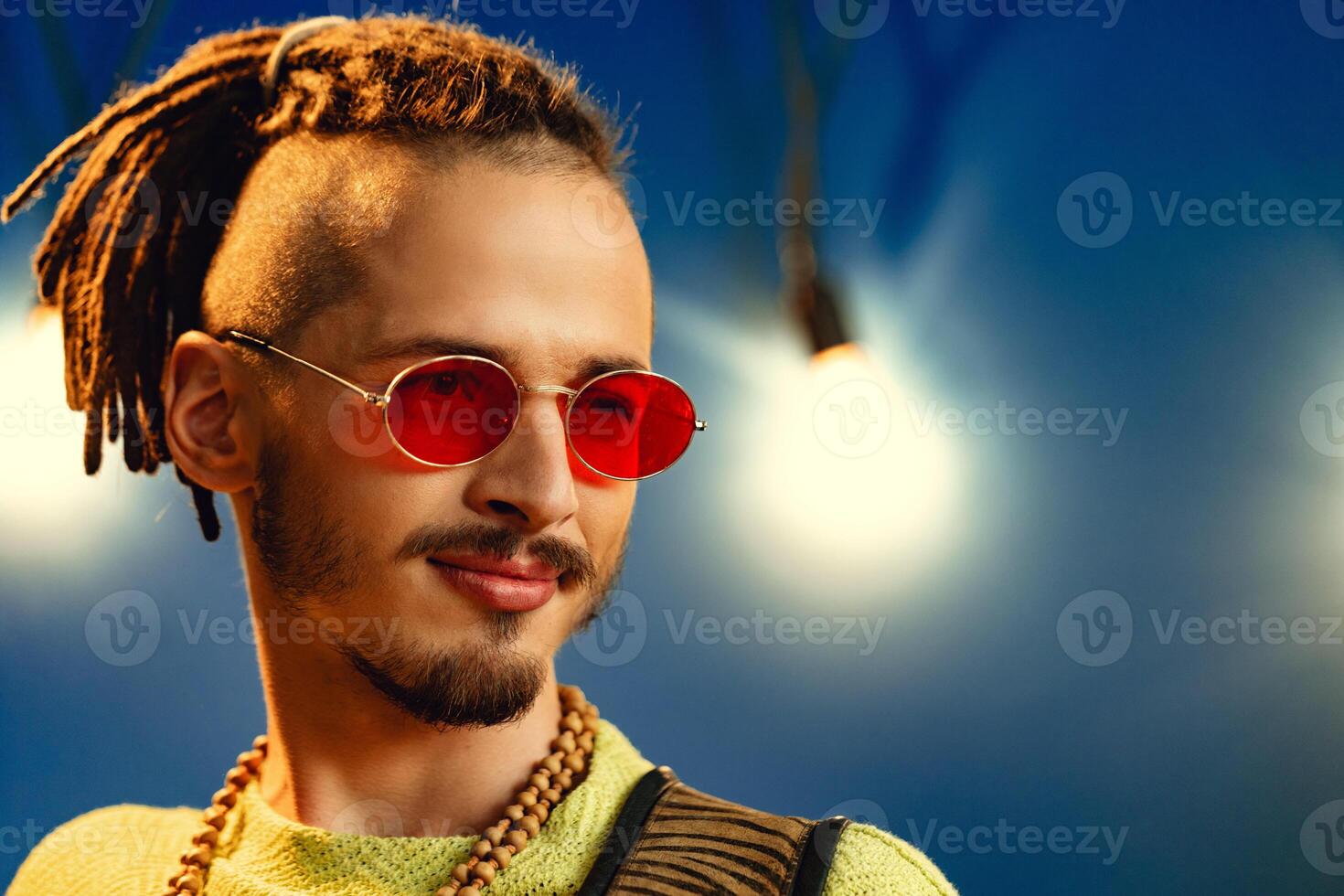 Portrait of a positive handsome caucasian guy with dreadlocks against blue background photo
