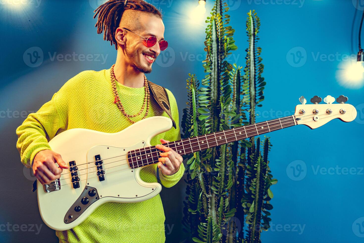 Cool guy with dreads practicing playing guitar at home photo