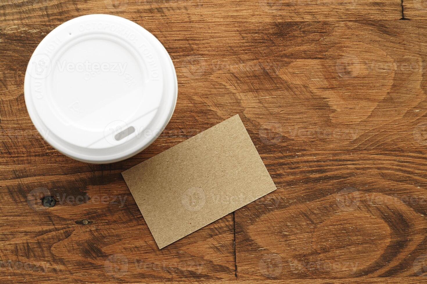 Takeaway coffee cup with blank business card on wooden table photo