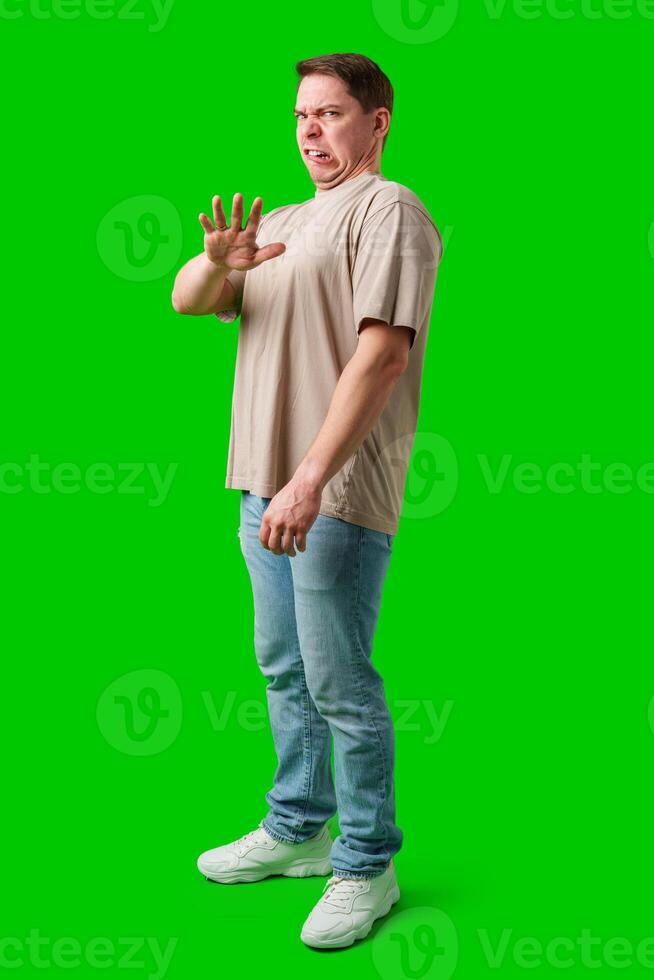 Young man making a disgusted expression while standing against a bright green background photo