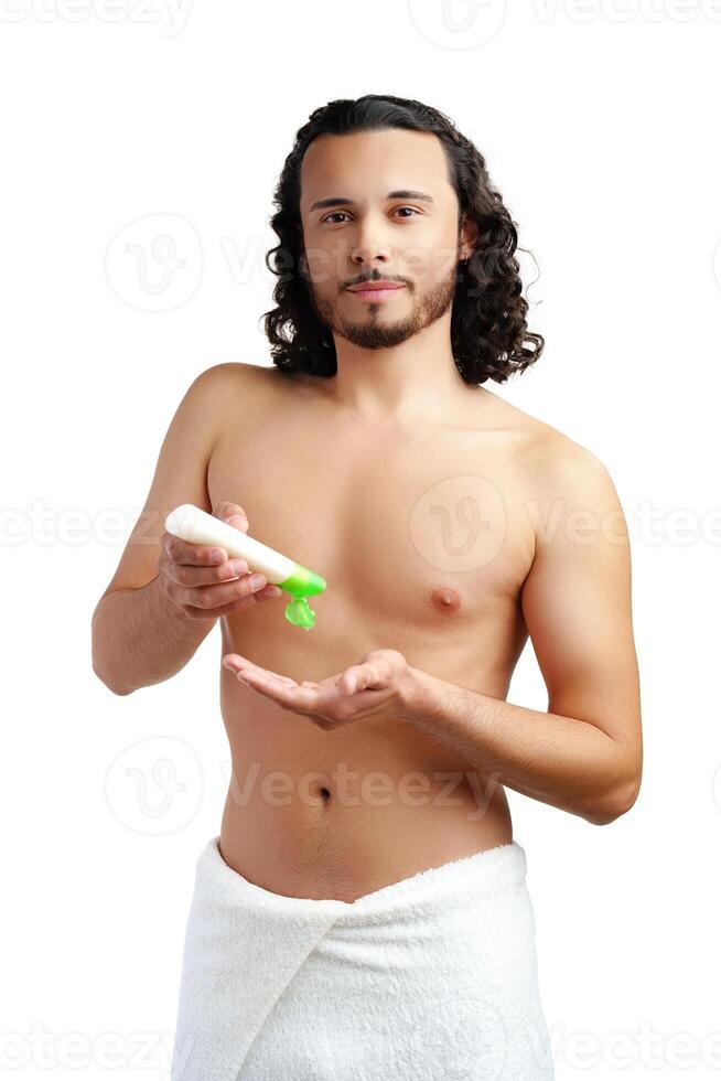 A young man applying skincare cream on his face with a focused expression, demonstrating personal grooming at home photo
