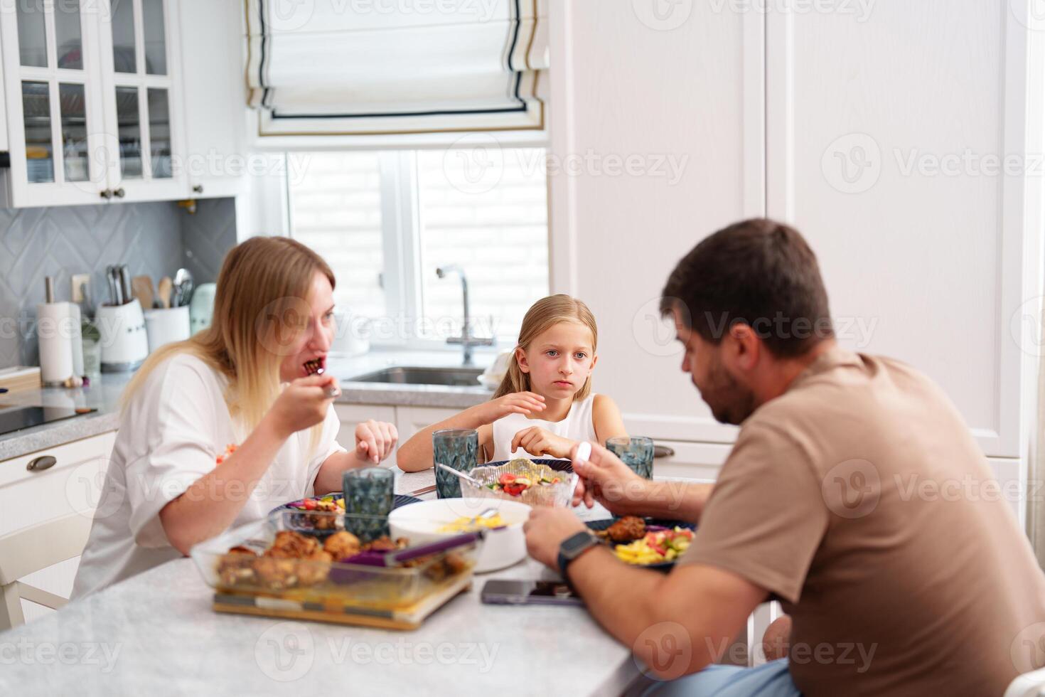 A family is eating dinner in their kitchen photo