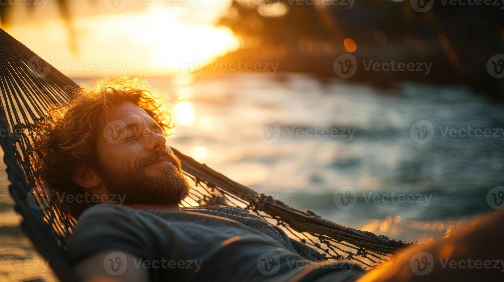 A man enjoys tranquility in a hammock as the sun sets over the calm water photo