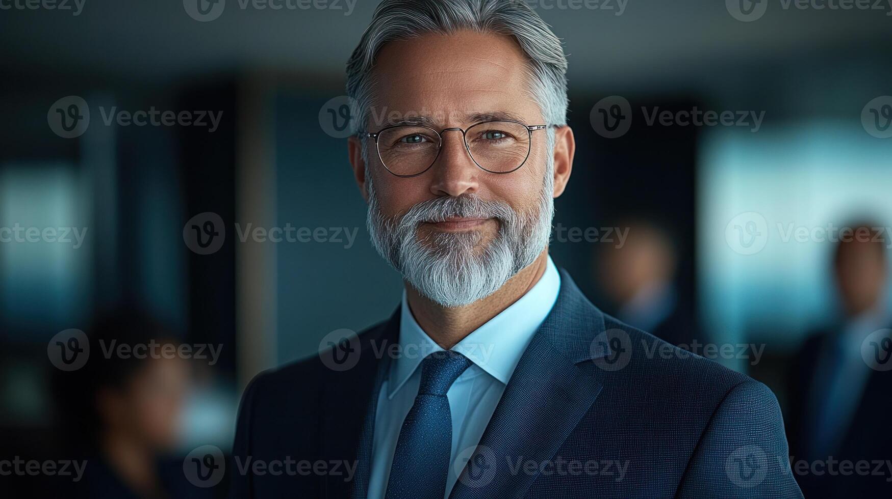 Businessman with glasses and gray beard stands confidently in a bright office space filled with colleagues photo