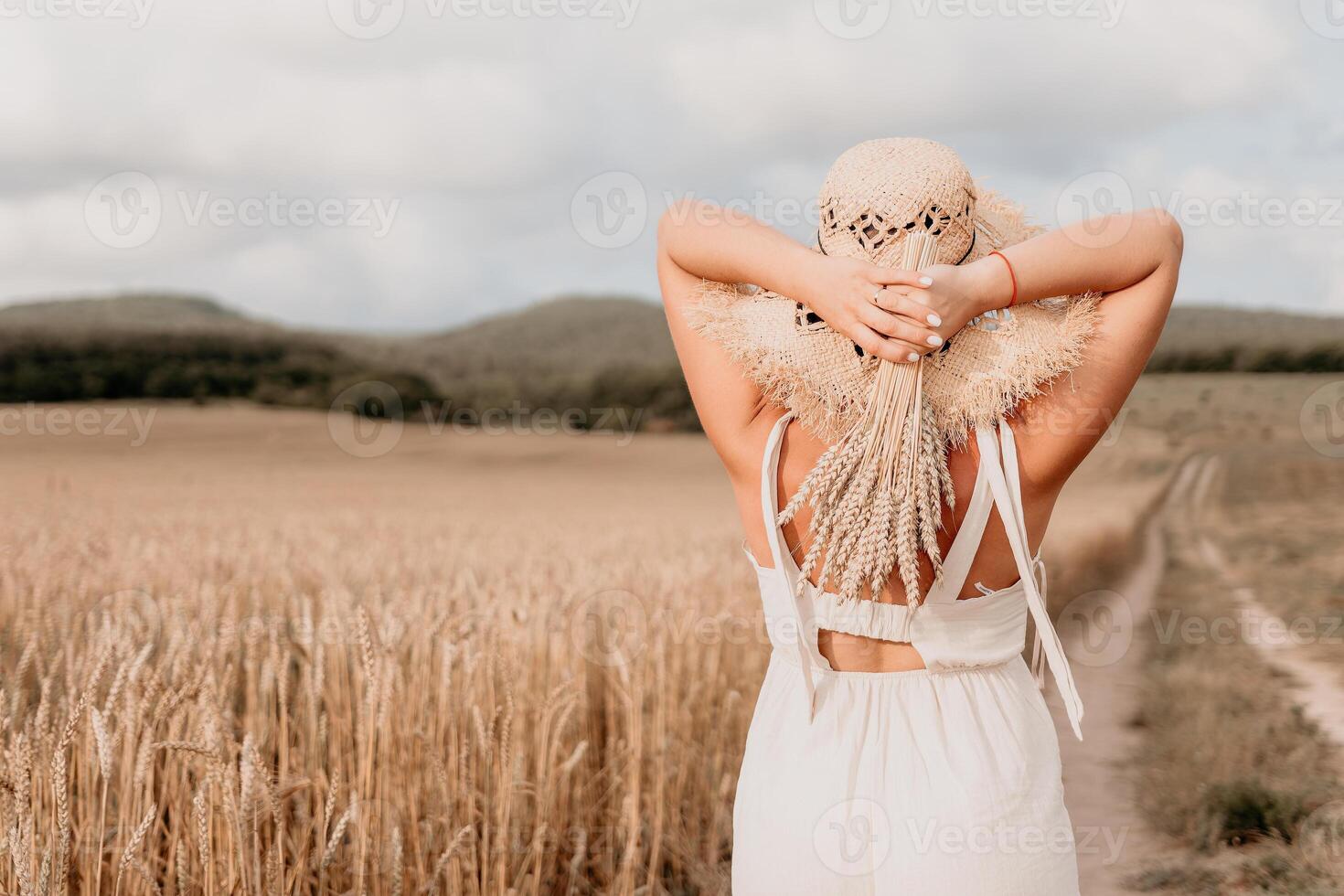 Woman in a White Dress and Straw Hat in a Wheat Field photo