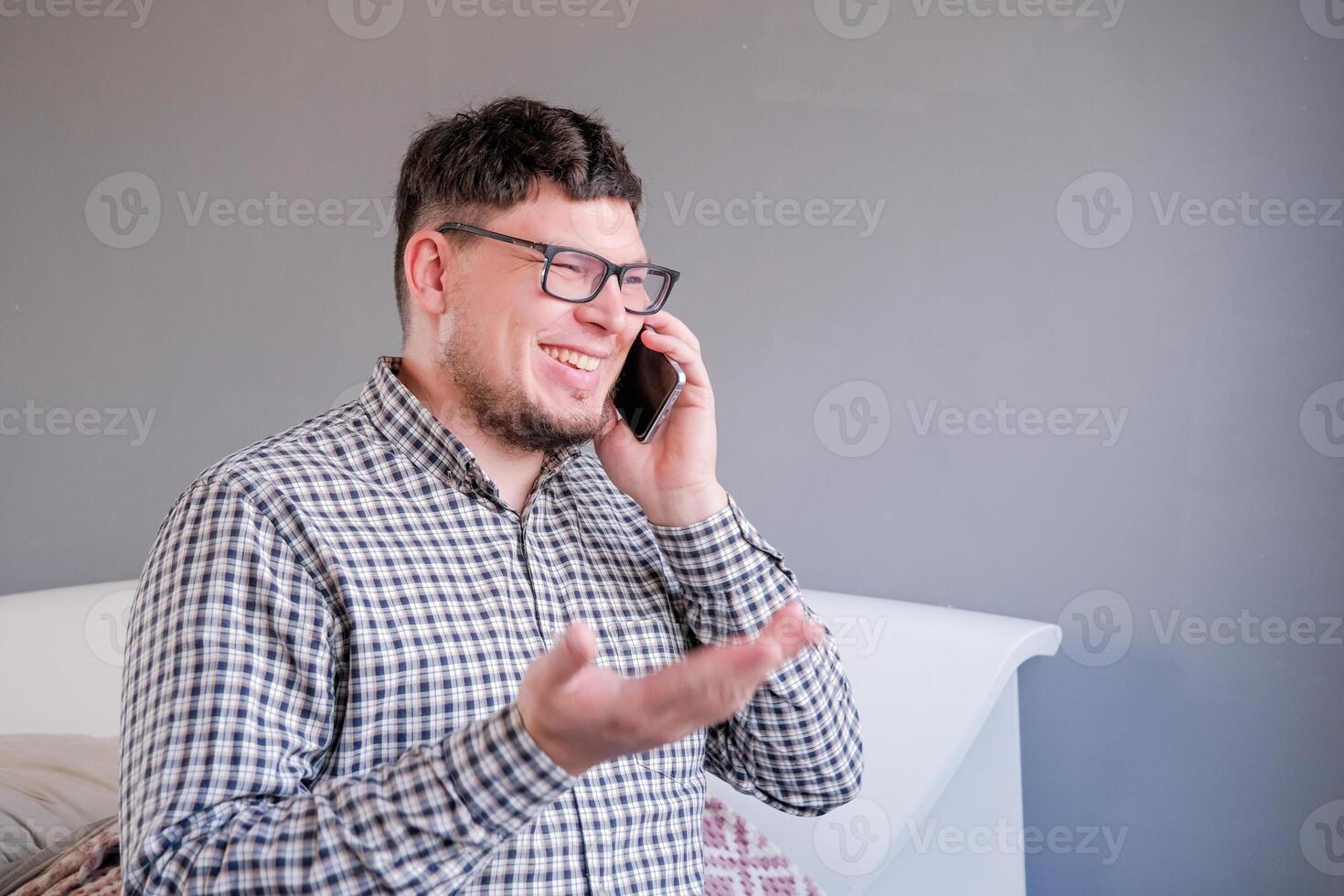 man sitting on the bed using smartphone having a call photo