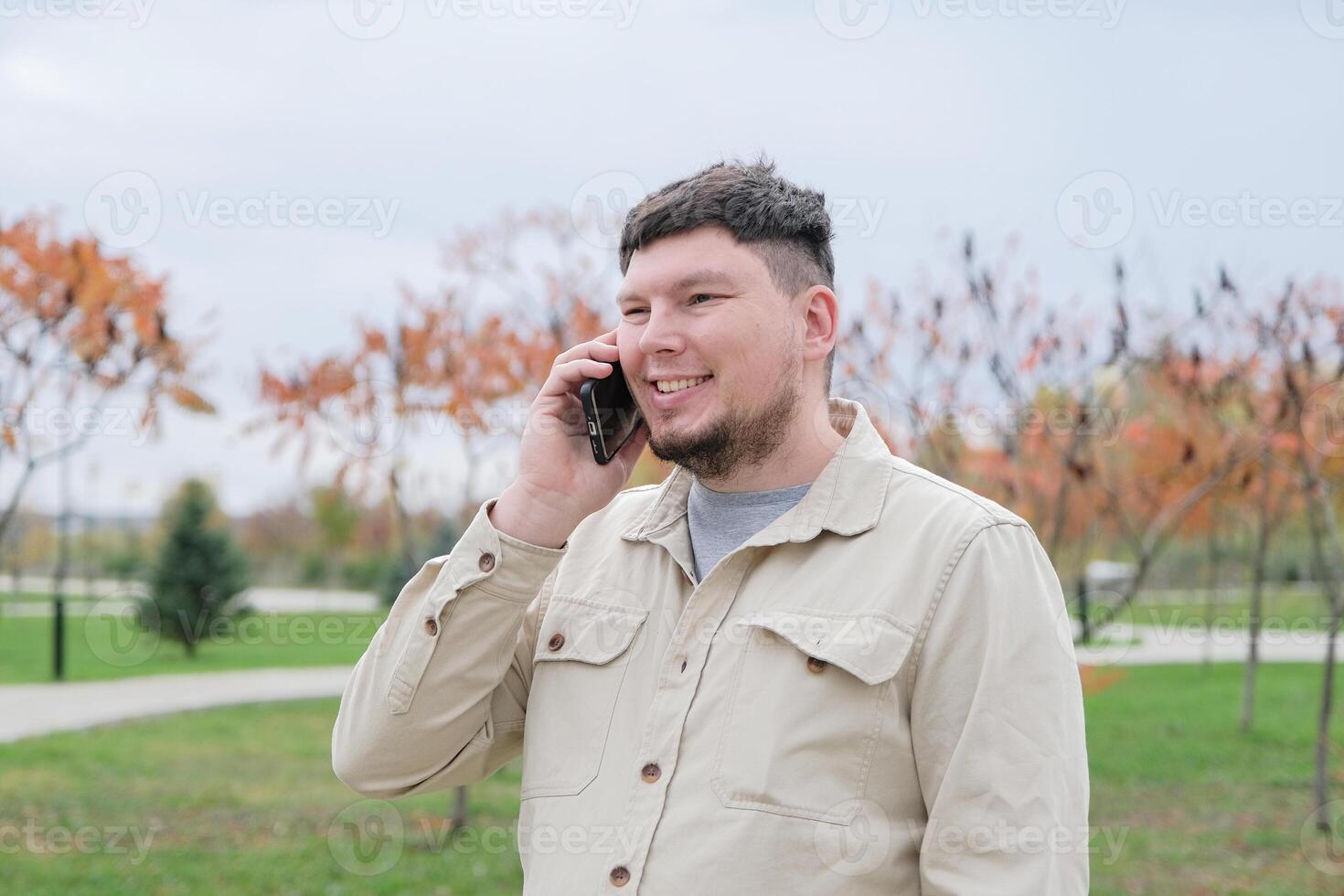 young caucasian man walking in the park and using smartphone photo