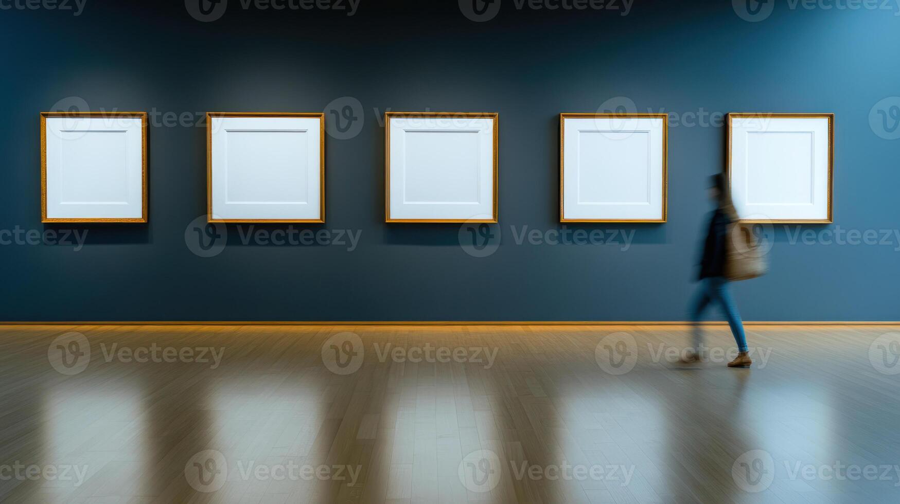 person walks past empty frames on dark blue wall in art gallery photo