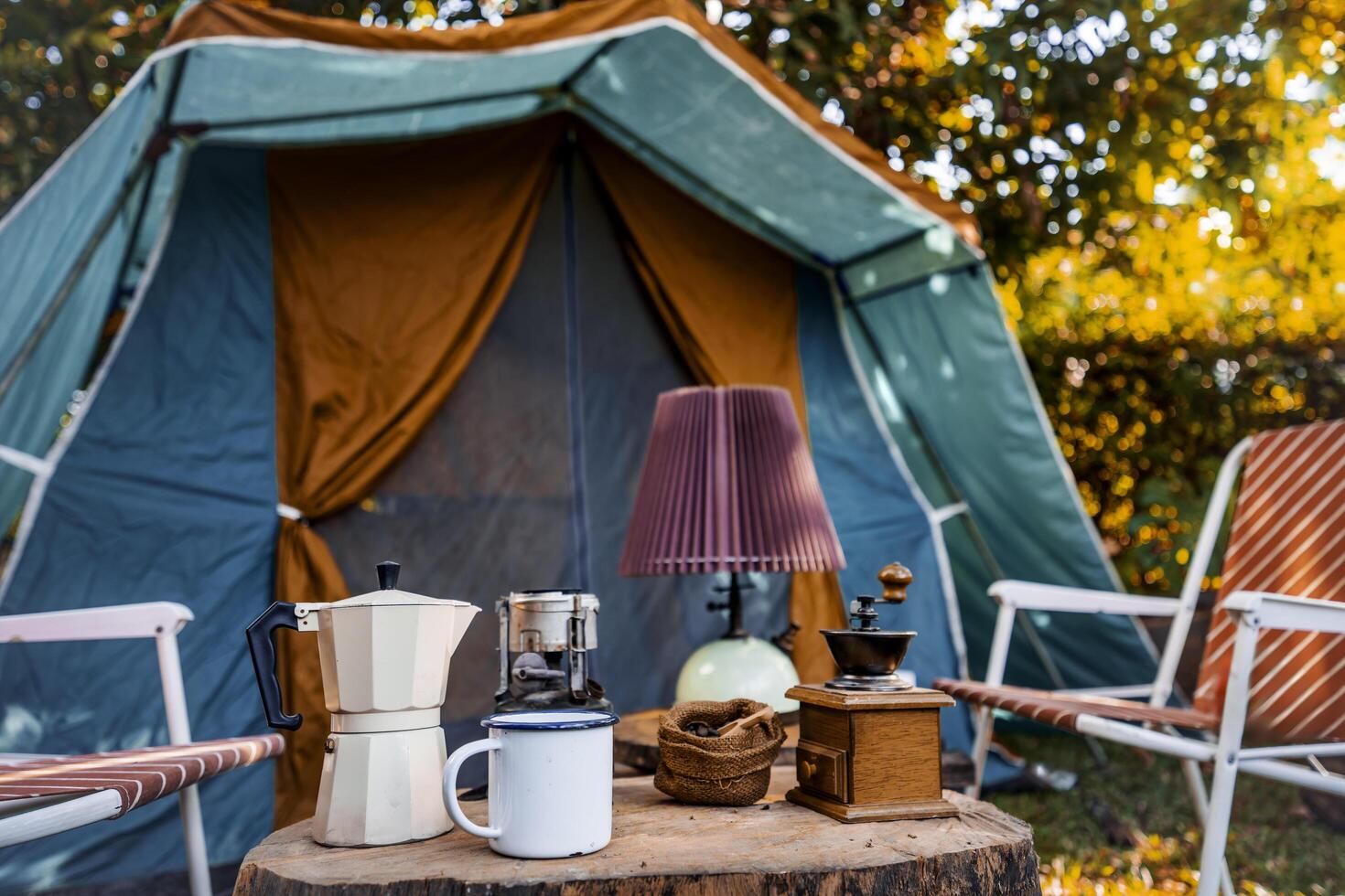 vintage coffee set on the old wooden table In front of the retro cabin tent, retro chairs, Group of camping tents, and soft focus. photo