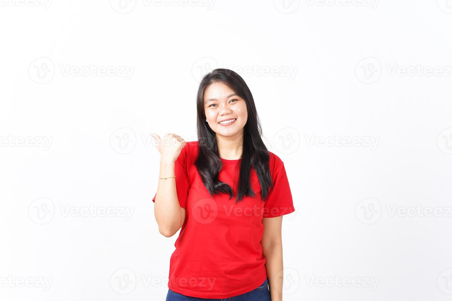 Smiling while Showing and Pointing Product With Thumb Of Beautiful Asian Woman wearing red shirt Isolated On White Background photo