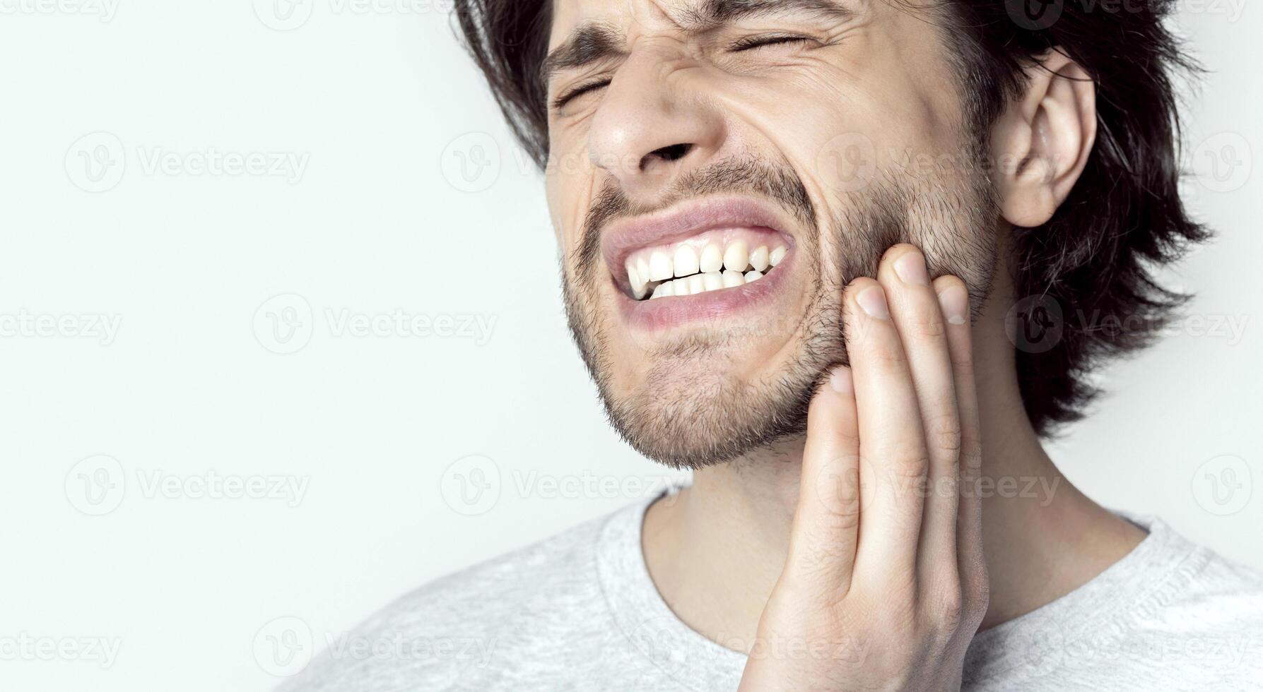 Toothache concept. Guy grimaces from pain, cropped photo