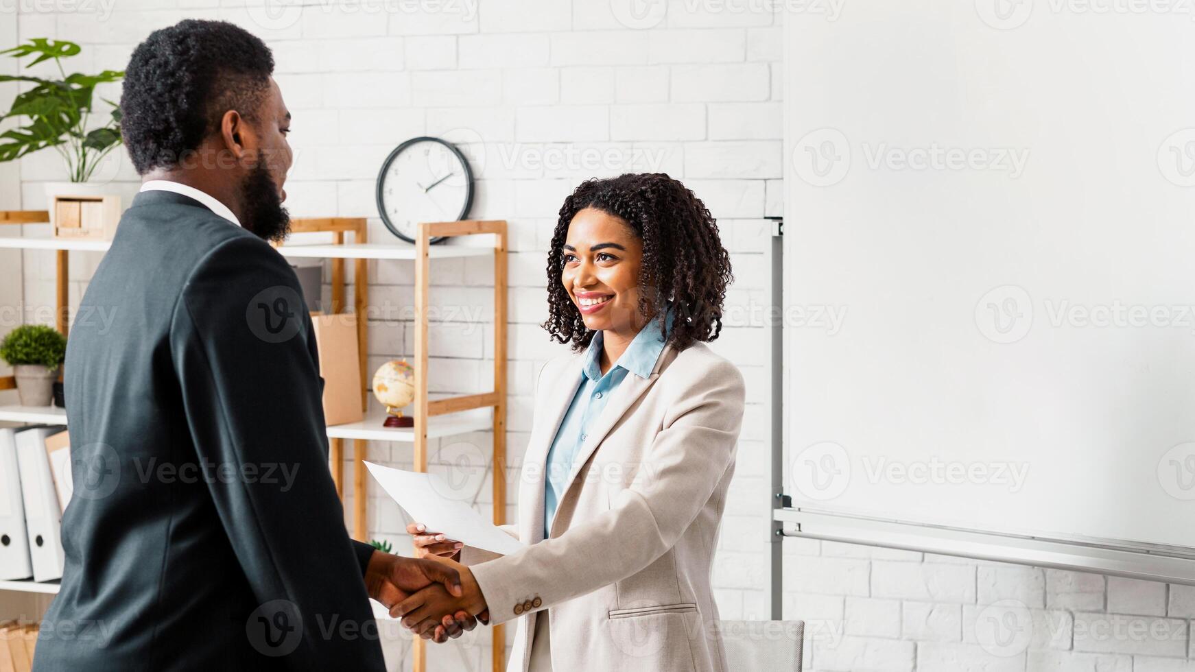 Smiling HR manager shaking hands with young applicant at job interview in office. Copy space photo