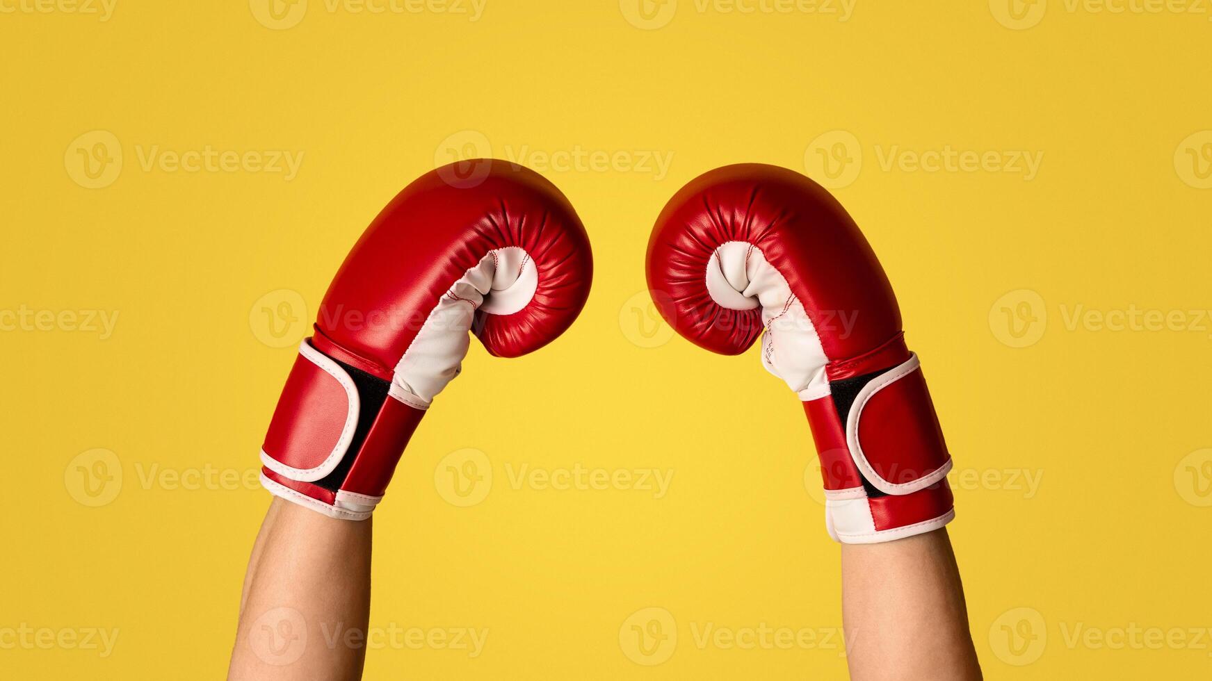 Unrecognizable fighter showing hands in boxing glove on orange background, closeup. Panorama photo