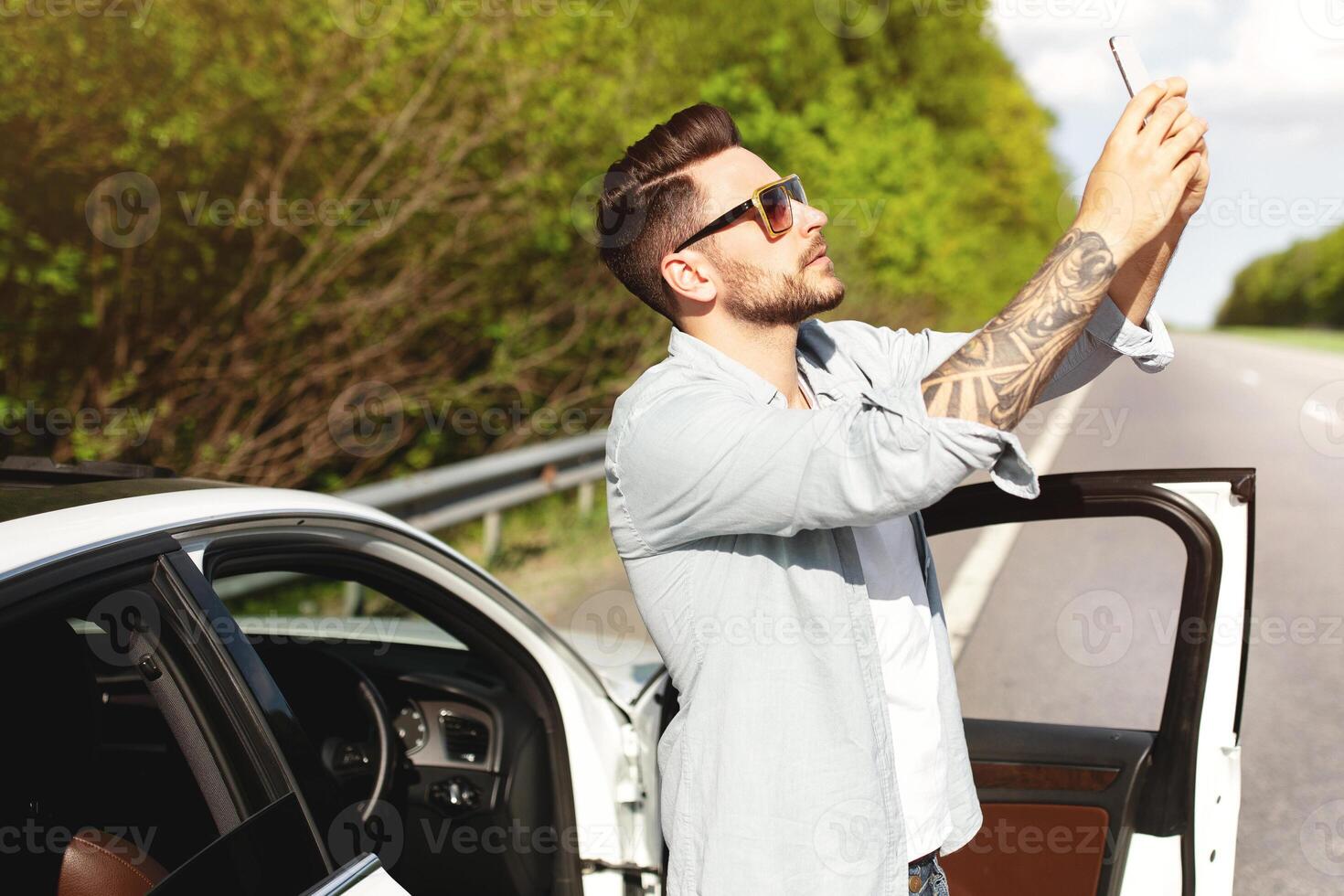 Unhappy Caucasian man standing near car, having problem with mobile connection, trying to find network on highway. Road emergencies, no signal, calling breakdown service concept photo