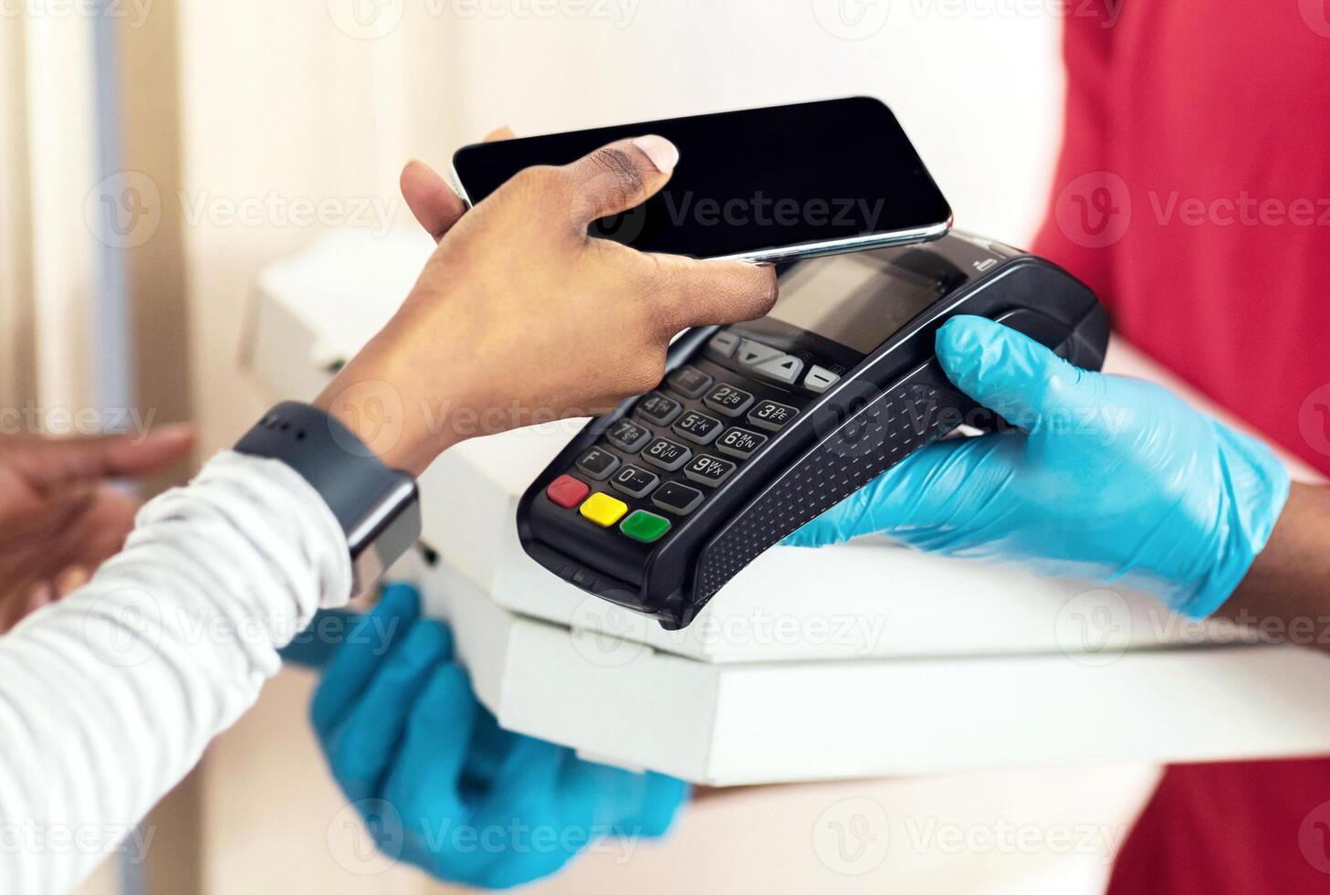 Mobile Payment For Food. Delivery. Unrecognizable Lady Paying Courier Using Smartphone And Terminal, Receiving Pizza Boxes Standing At Home. Cropped Shot, Panorama, Selective Focus photo