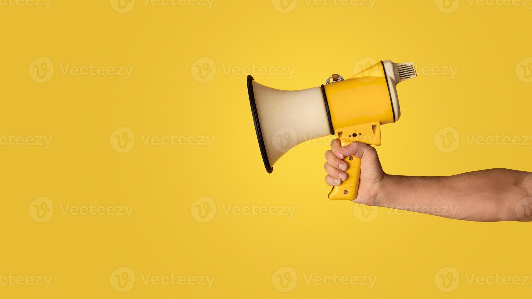 Advertising concept. Millennial guy holding loudspeaker on orange background, closeup. Panorama photo