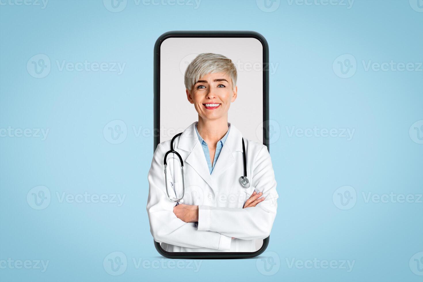 Friendly doctor waiting for patient concept. Smiling woman in white coat with crossed arms and stethoscope, isolated on light background photo