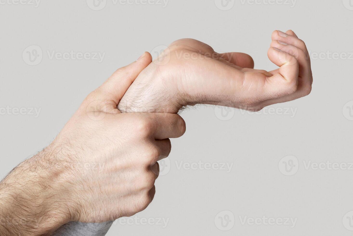 Wrist pain. Man massages joint in his hand isolated on light background photo