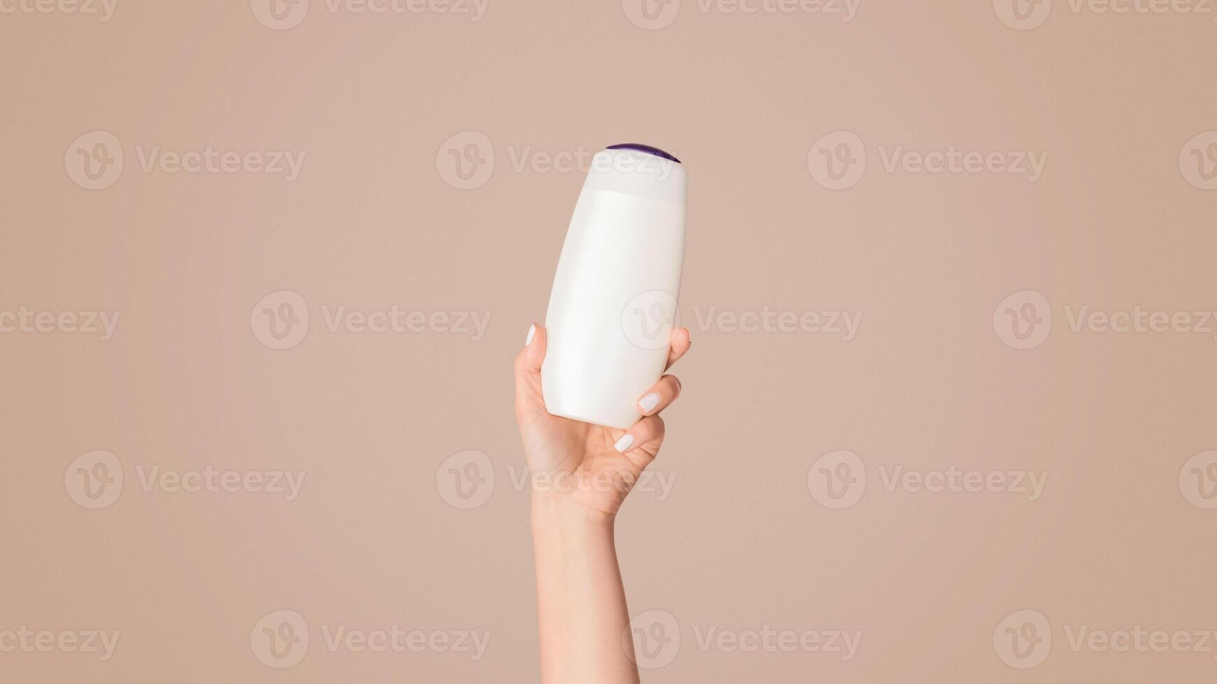 Girl showing bottle of shampoo, lotion or shower gel with mockup for design on pink background, closeup. Panorama photo