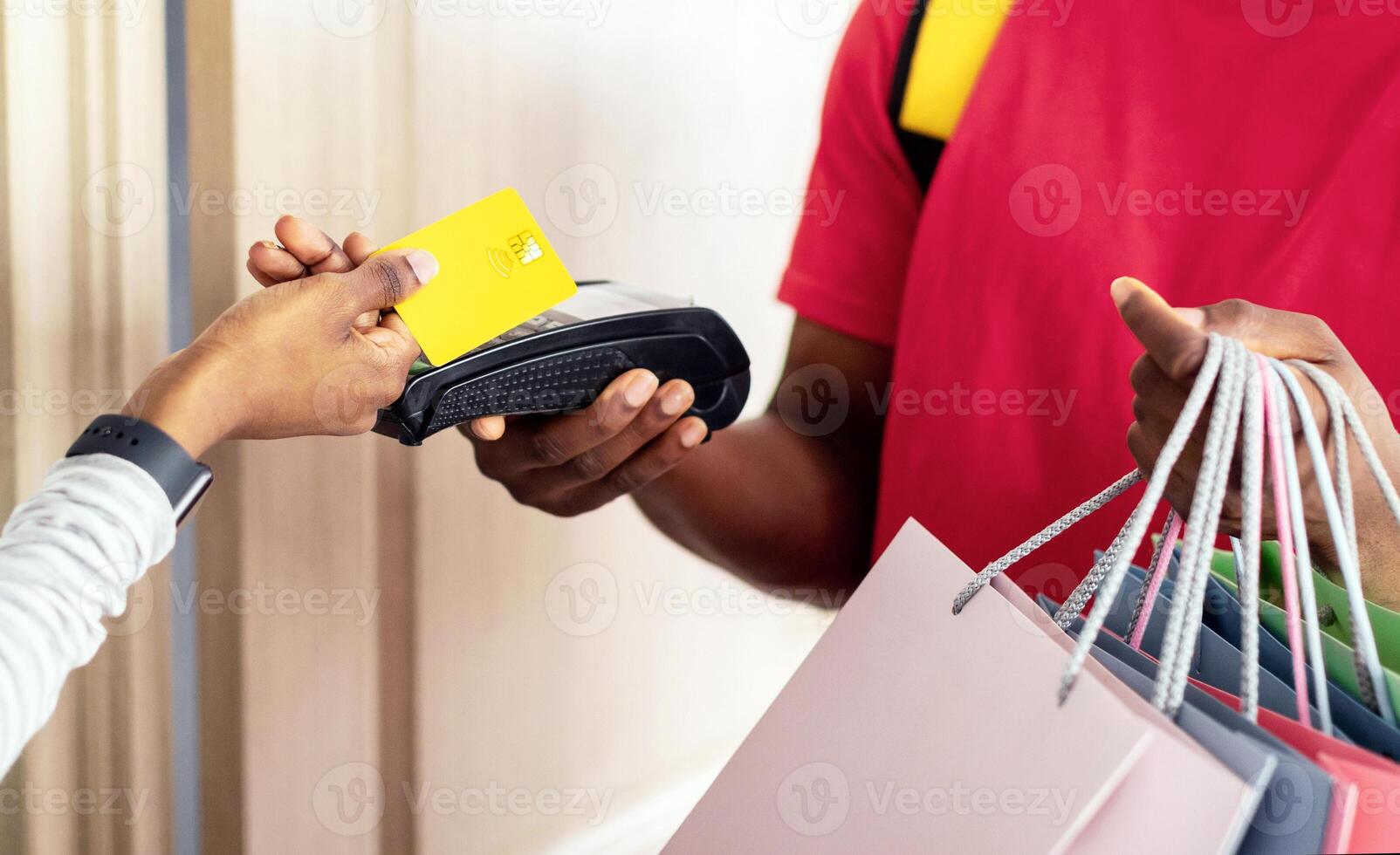African American Woman Making Payment With Credit Card And Terminal Paying Courier Guy For Shopping Bags Delivery From Store At Home. Modern Shopping And Consumerism Concept. Cropped, Panorama photo