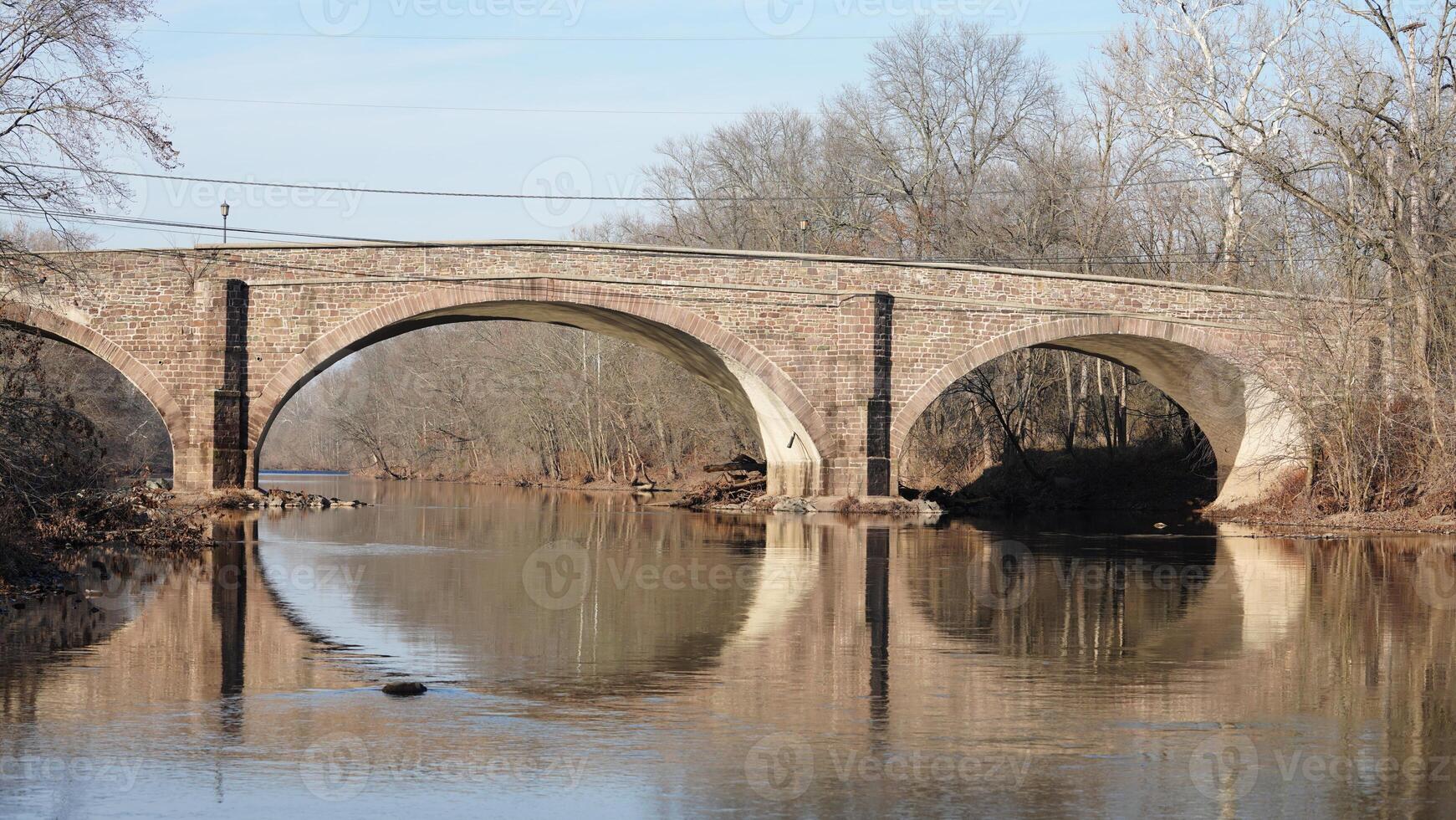One old arched bridge cross above the river in the countryside of the USA photo
