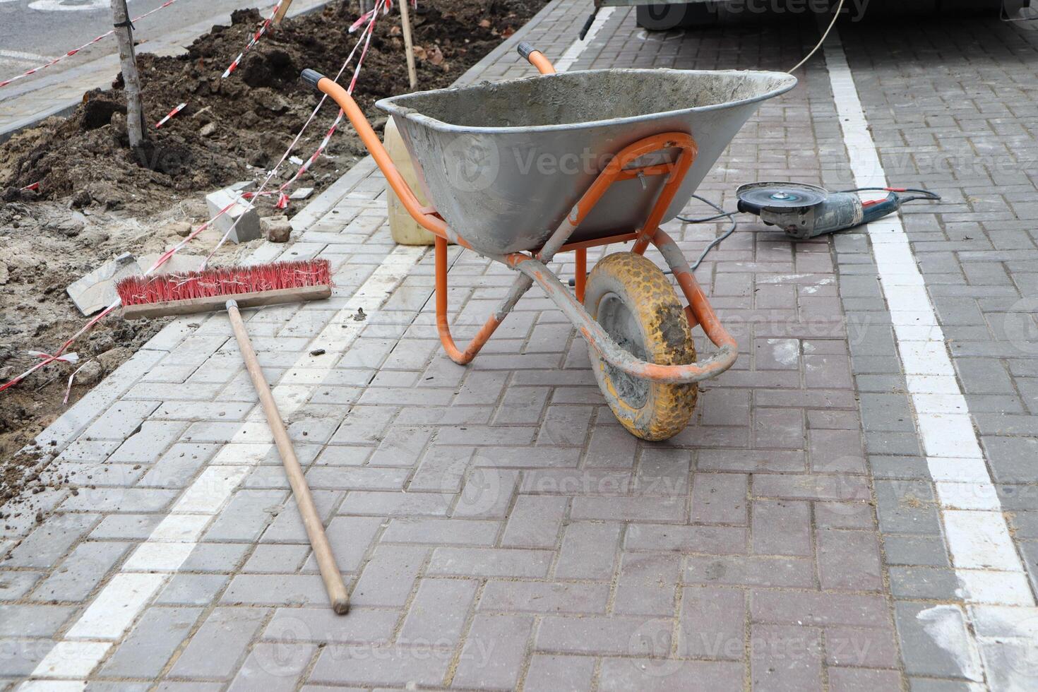 A Construction Site featuring a Wheelbarrow prominently placed alongside a Warning Sign photo