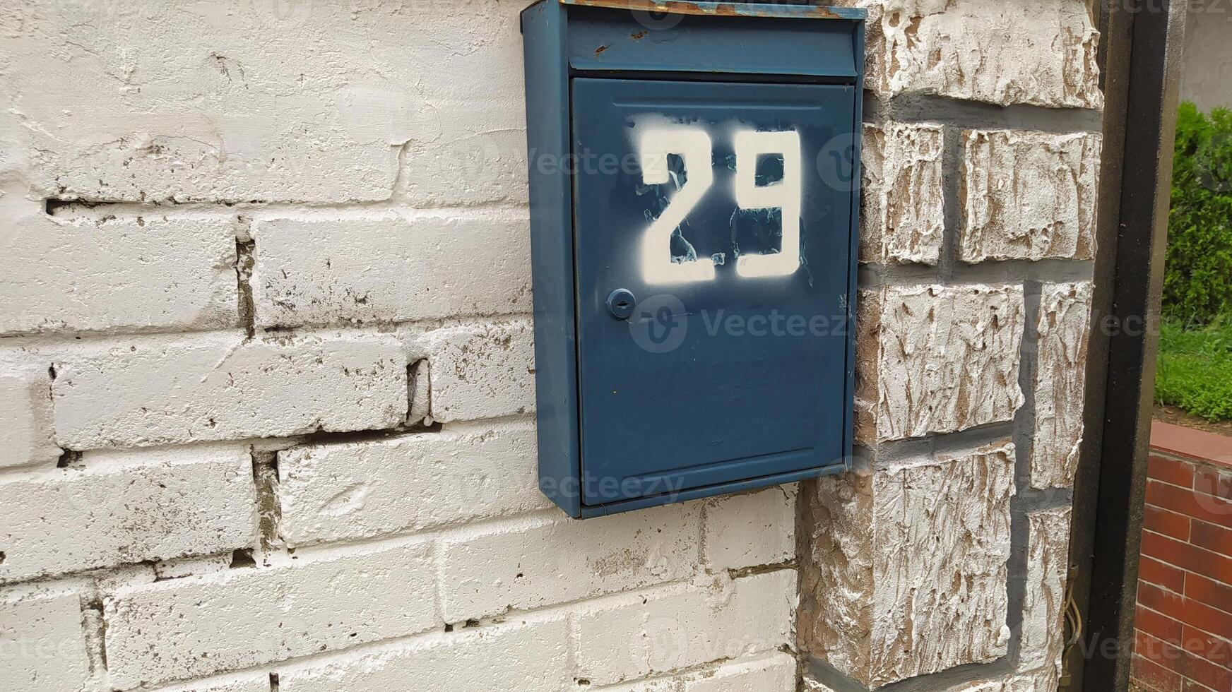 A charming blue mailbox featuring the number 29 beautifully affixed to a classic brick wall photo