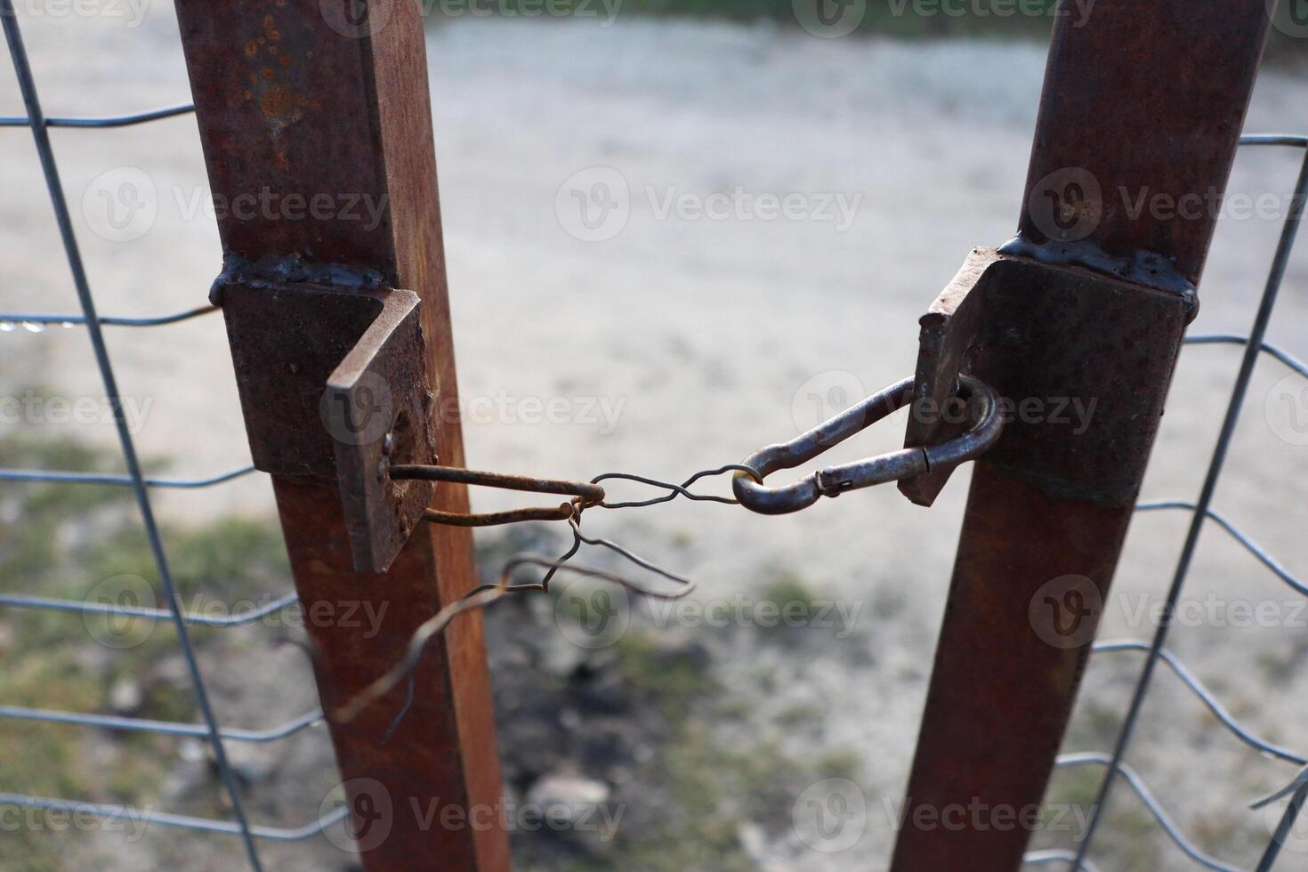 A rusty old fence gate with a simple locking mechanism that guarantees security and privacy photo