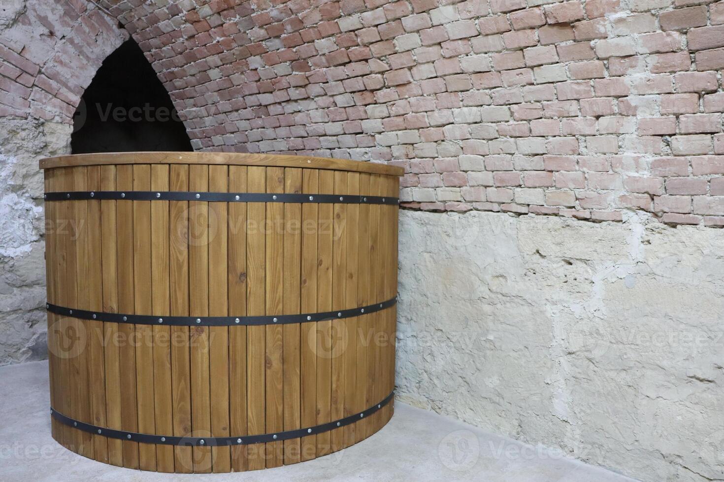 A rustic wooden barrel is elegantly placed in an arched cellar, highlighting its charm photo