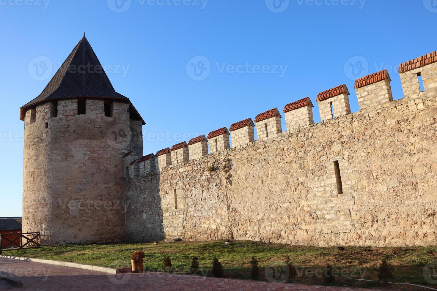 An impressive historic stone tower and wall gracefully set against a brilliant blue sky photo