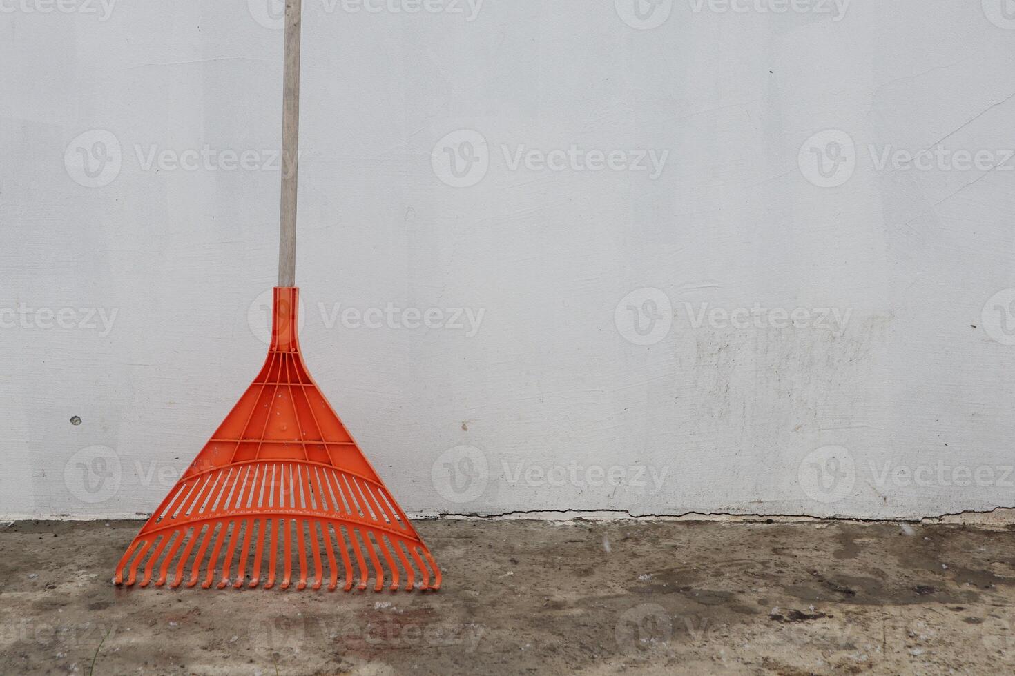 A Vibrant Orange Rake Placed Against a Simple Yet Striking Background for Context and Focus photo