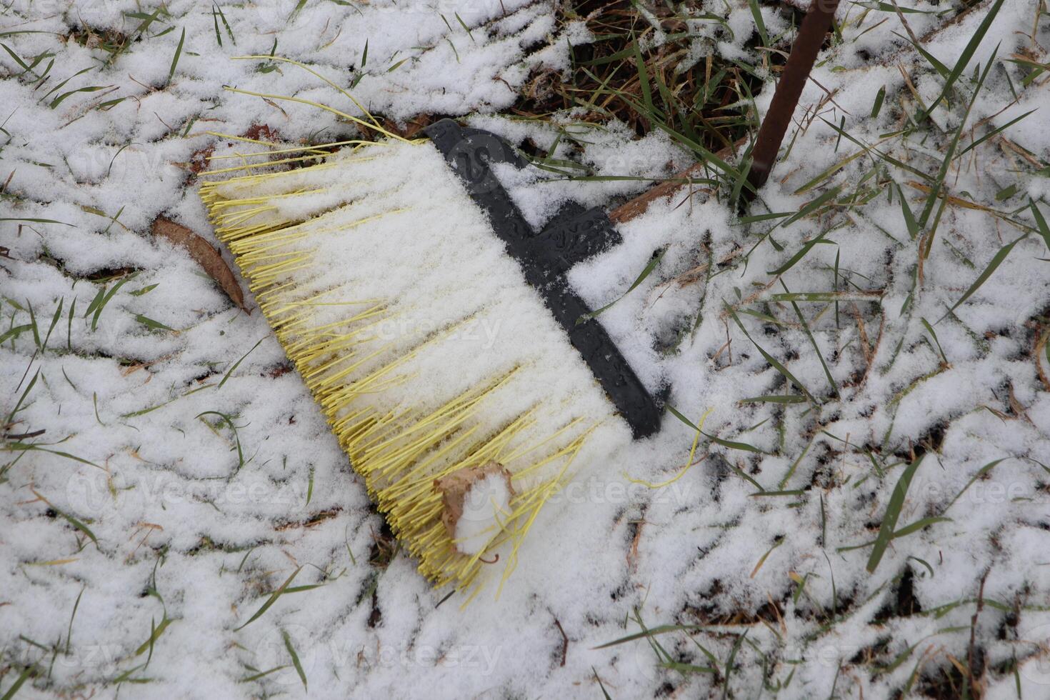 A SnowCovered Broom Left Abandoned on the Cold Ground Surrounded by the Wintery Landscape photo