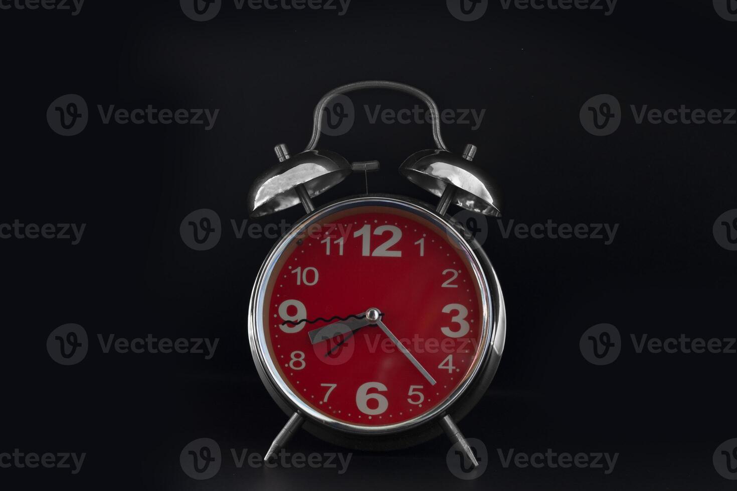 a red alarm clock on a black background photo