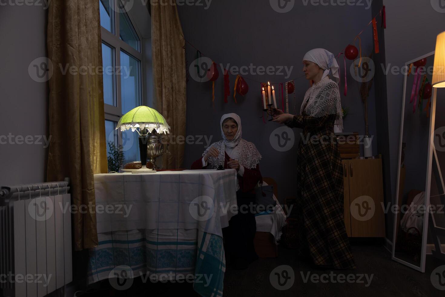 Two women in a room with a table and a lamp photo