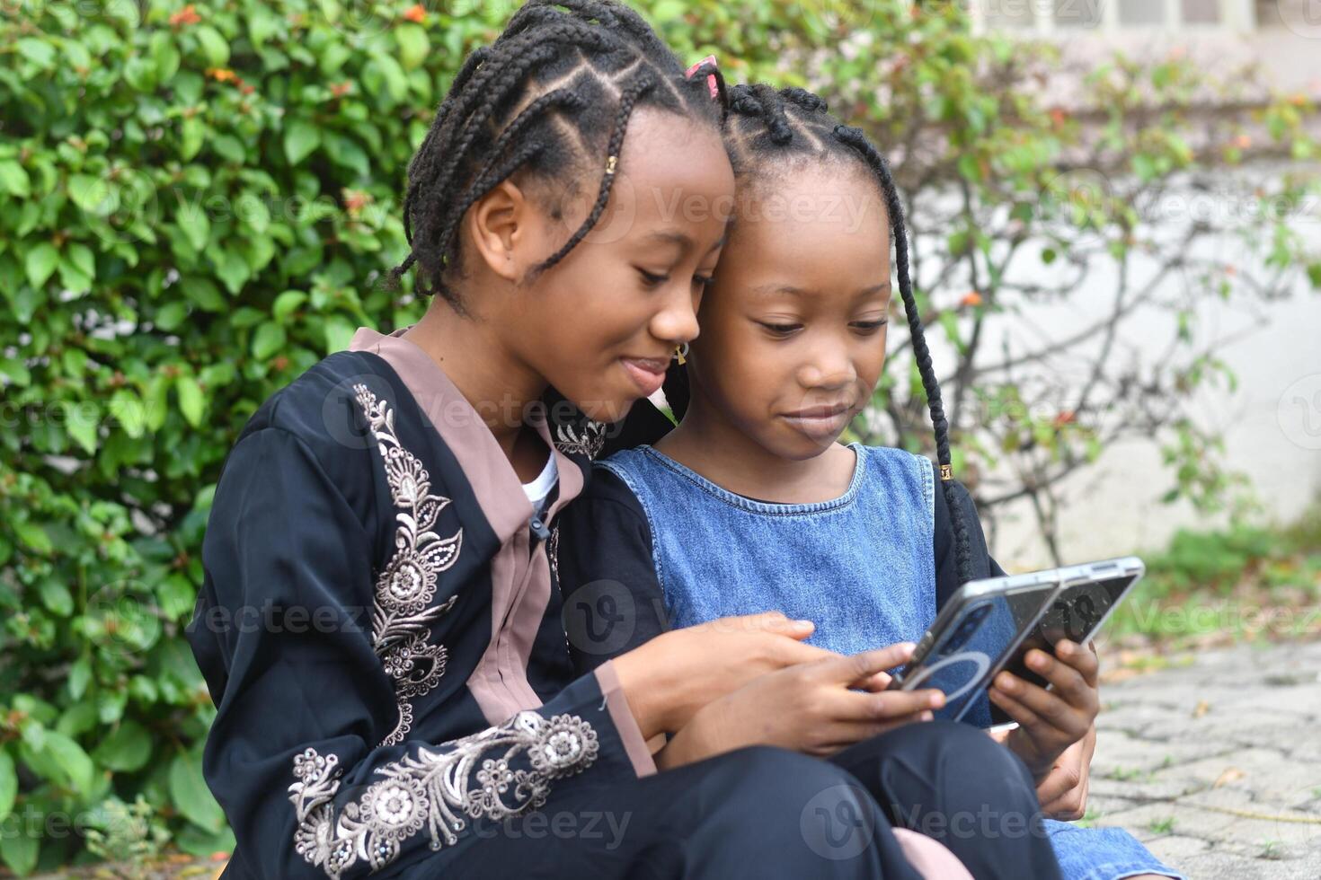 A heartwarming and lively image of two sisters enjoying their time together while using a cellphone. photo